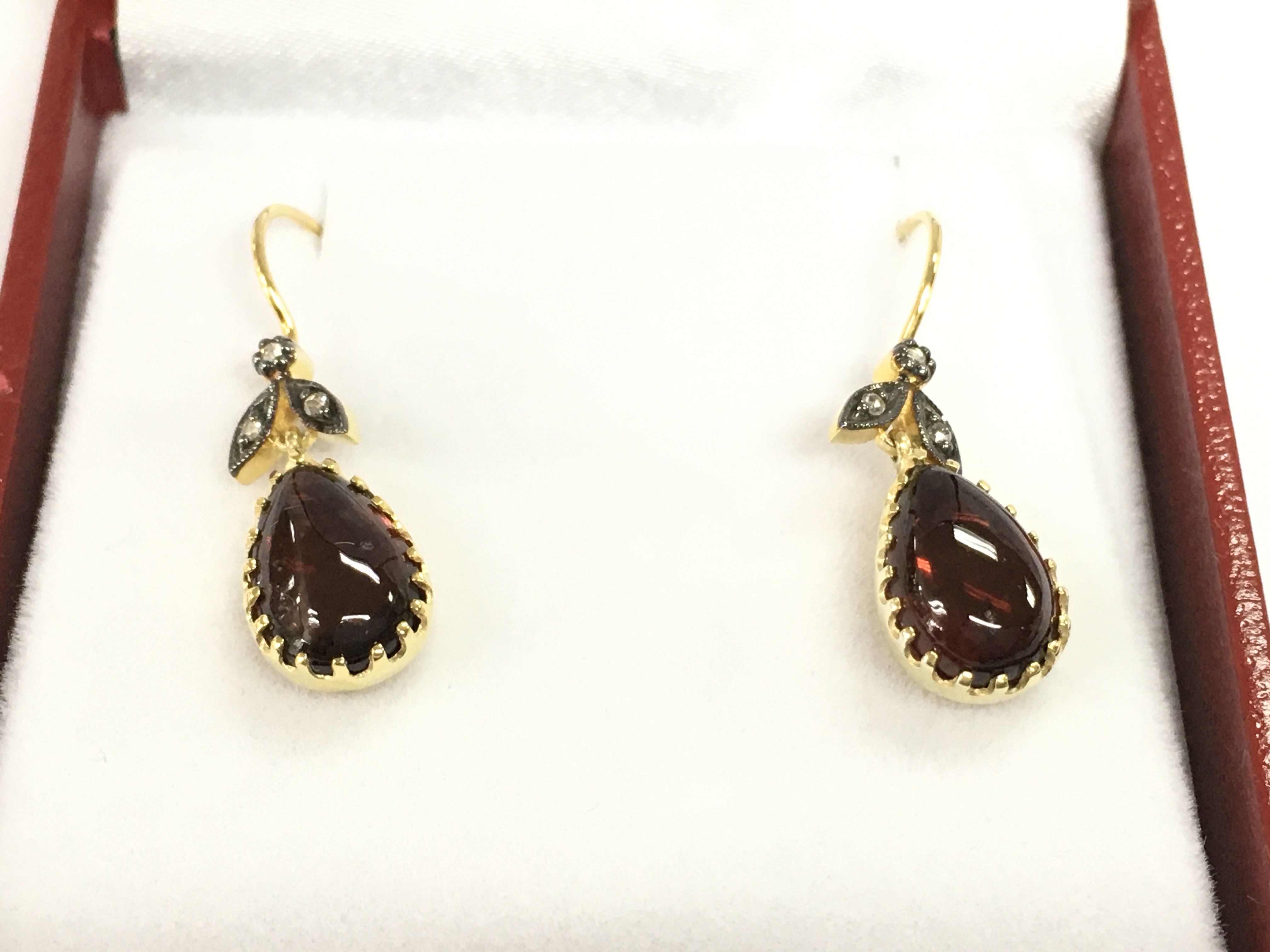 Pair of 9ct yellow gold and silver drop earring set with oval cabochon garnet with rose cut diamonds set to foliate bale with fish hook fitting. Garnet 2.80ct diamonds 0.06ct.