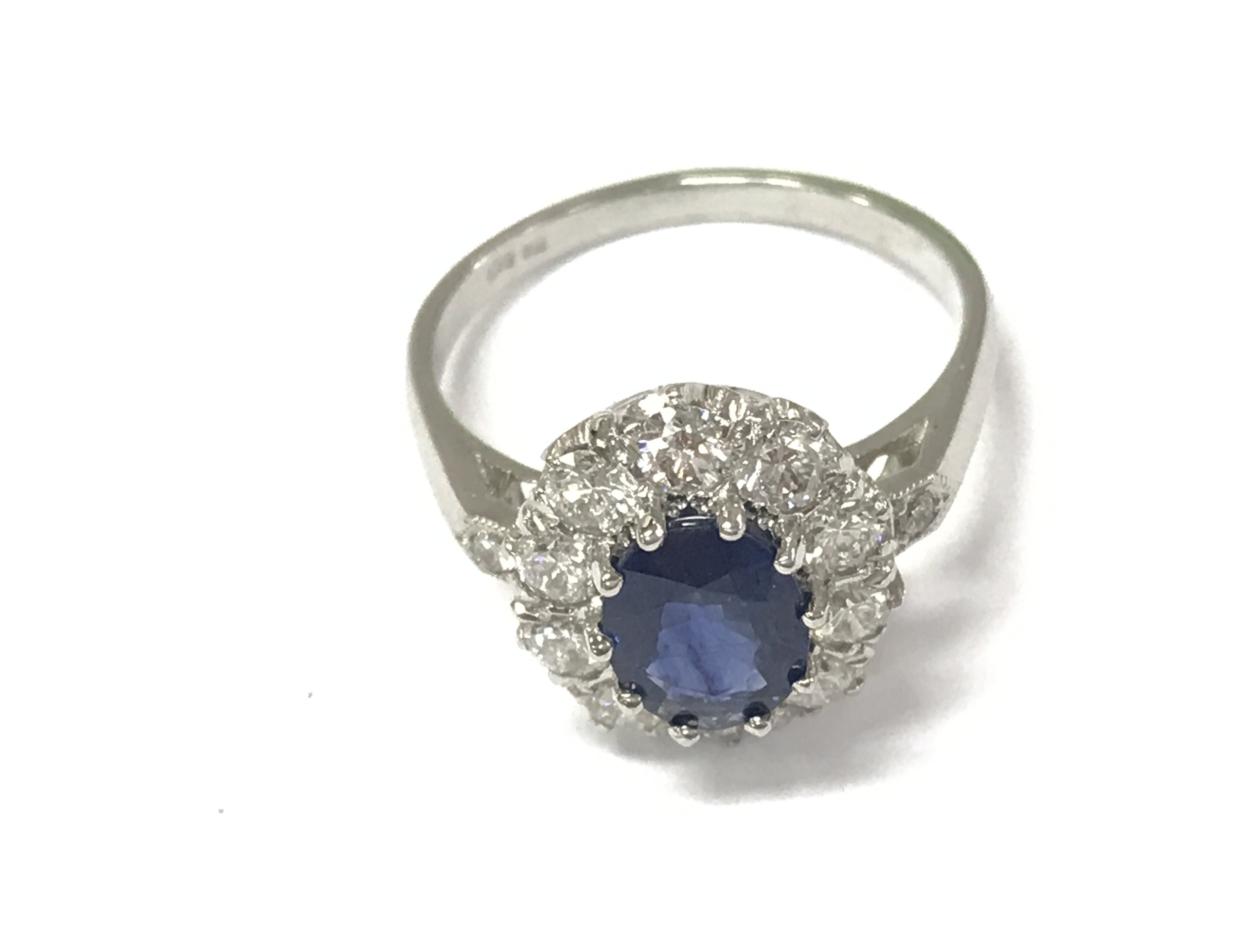 A platinum ring set with an oval sapphire a halo of diamonds and diamond set shoulders. Sapphire 1.50ct diamonds 0.85ct approximately. Size N