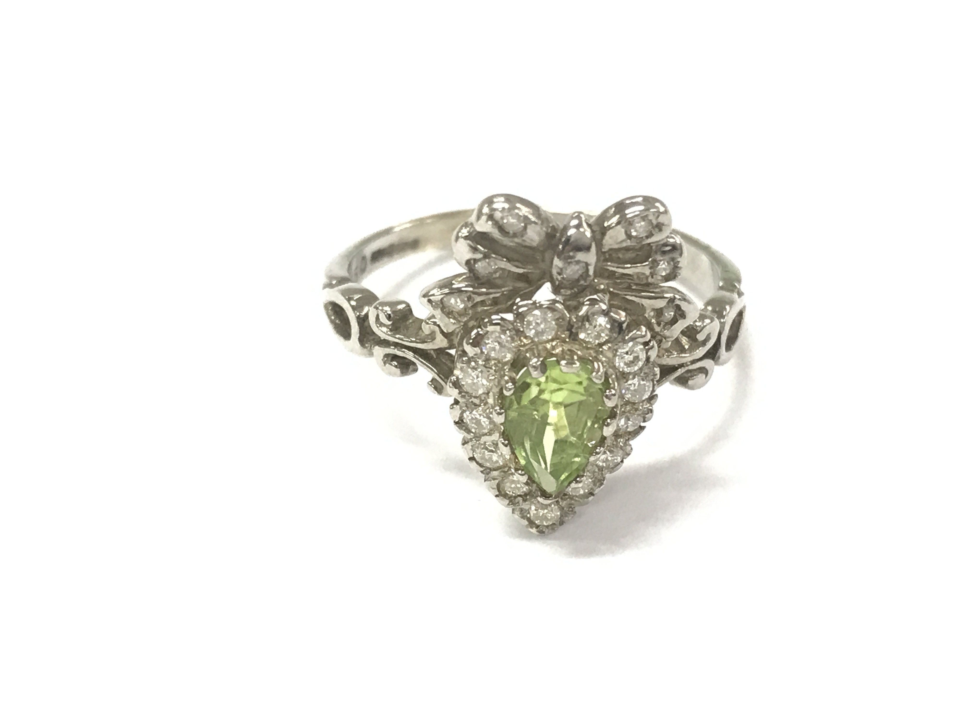 A 9ct white gold bow style ring set with pear shaped peridot and diamonds. Peridot 0.96ct and diamonds 0.50ct approximately. Size L