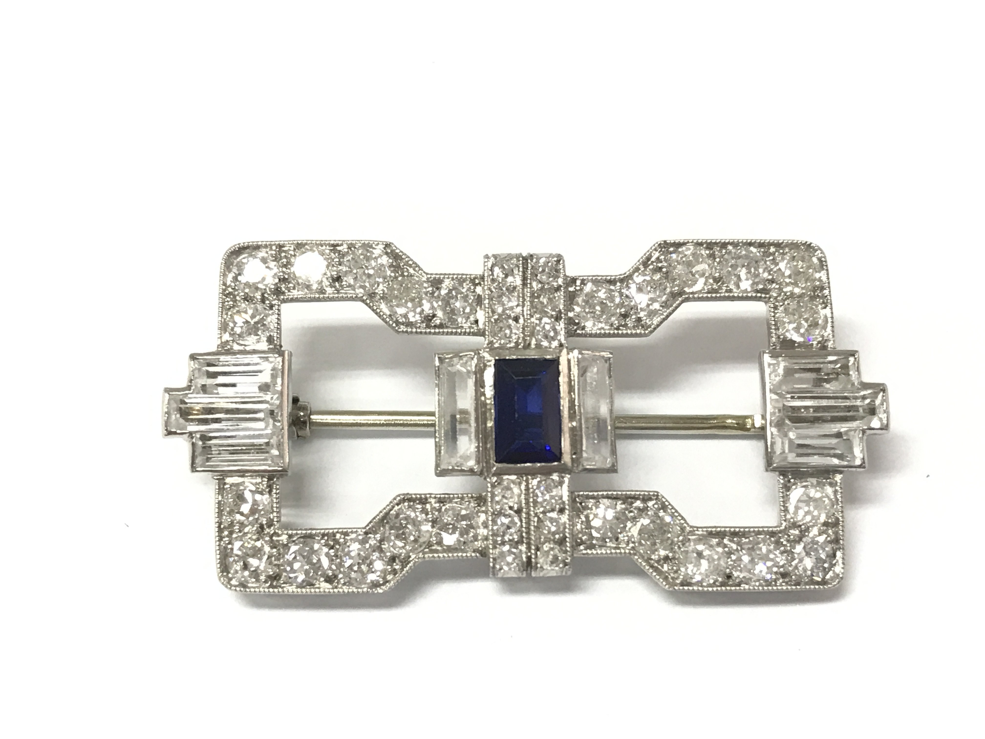 An art deco brooch in white metal set with old cut diamonds and further white and blue gemstones. Postage A