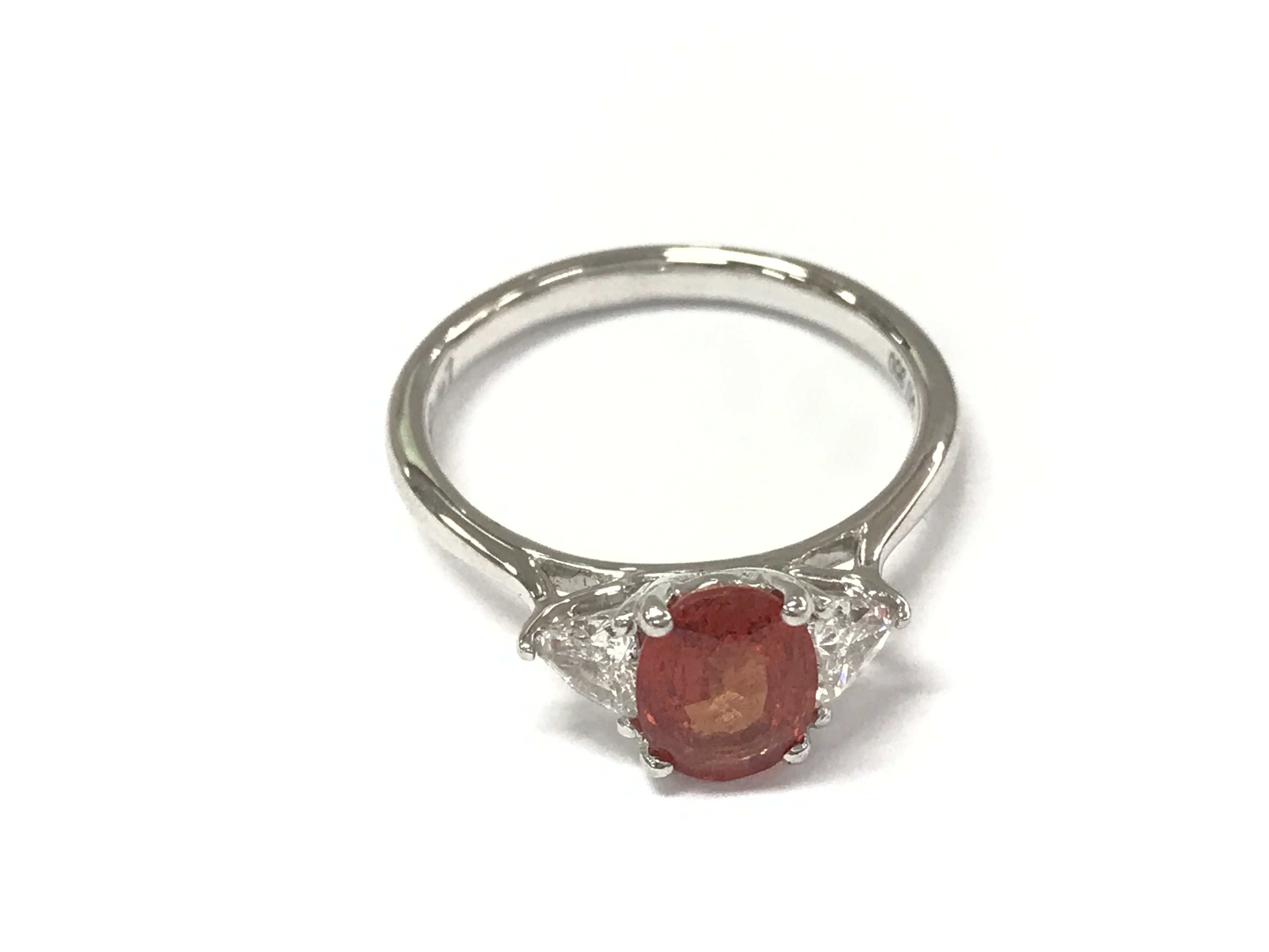 Platinum trilogy ring set with a central oval orange sapphire flanked by diamonds. Sapphire 1.37ct and diamonds 0.37ct. Size N