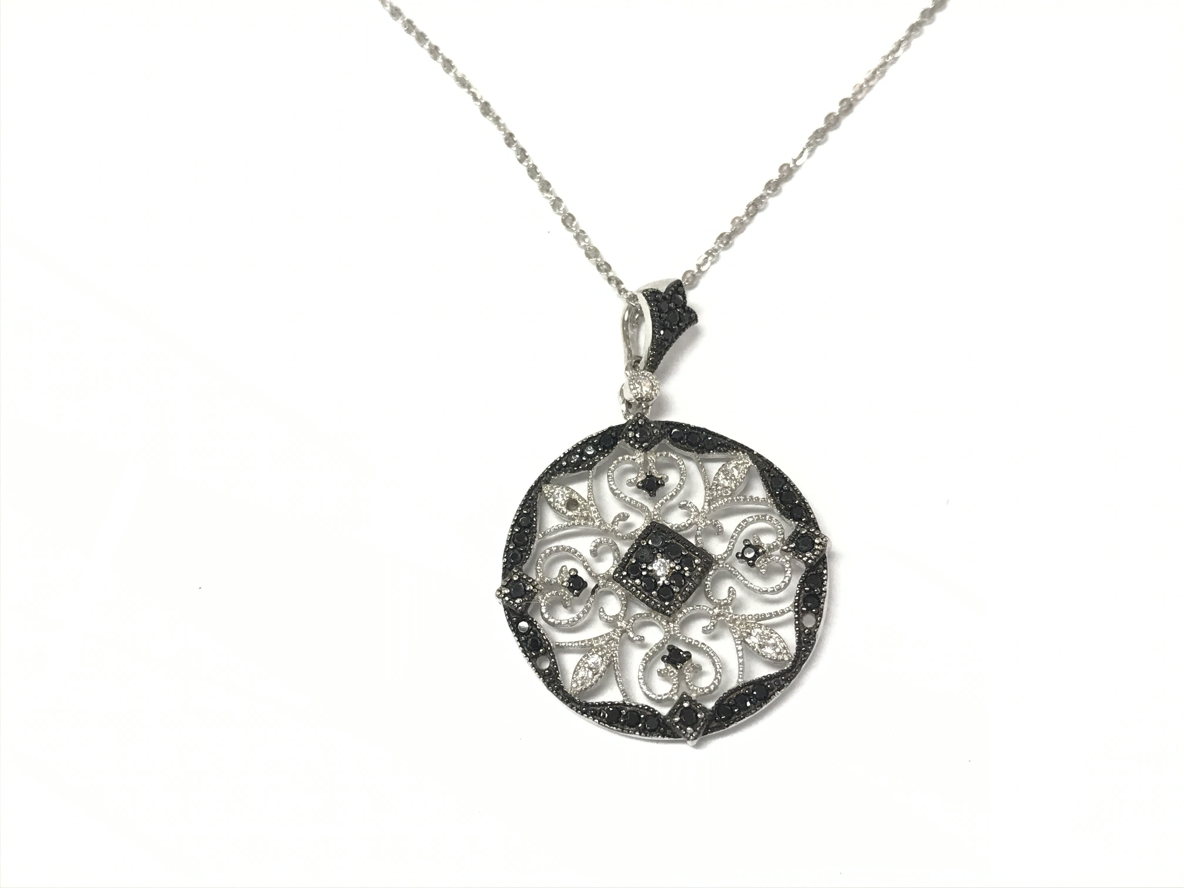 An ornate open work silver pendant set with black and white CZ on a silver chain.