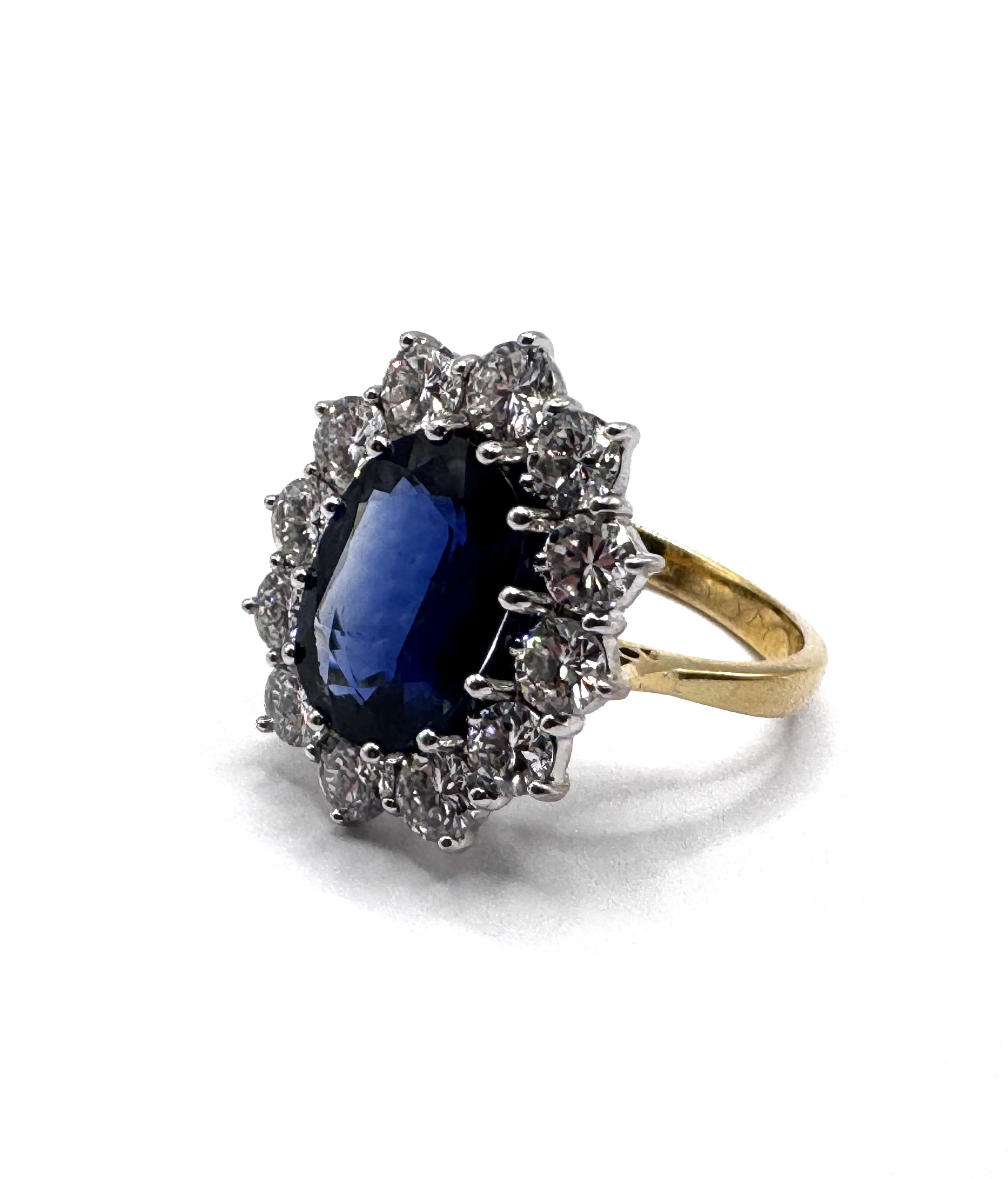 4.80 Carat CAMBODIAN SAPPHIRE AND DIAMOND CLUSTER RING set with an oval cut sapphire of 4.80 carats in a cluster of round brilliant cut diamonds, the diamonds totalling approx 3.30ct F-G colour, VS1-VS2, Fully Hallmarked for 18ct gold, size Q.5, 8.28g. With WGI report. (A)