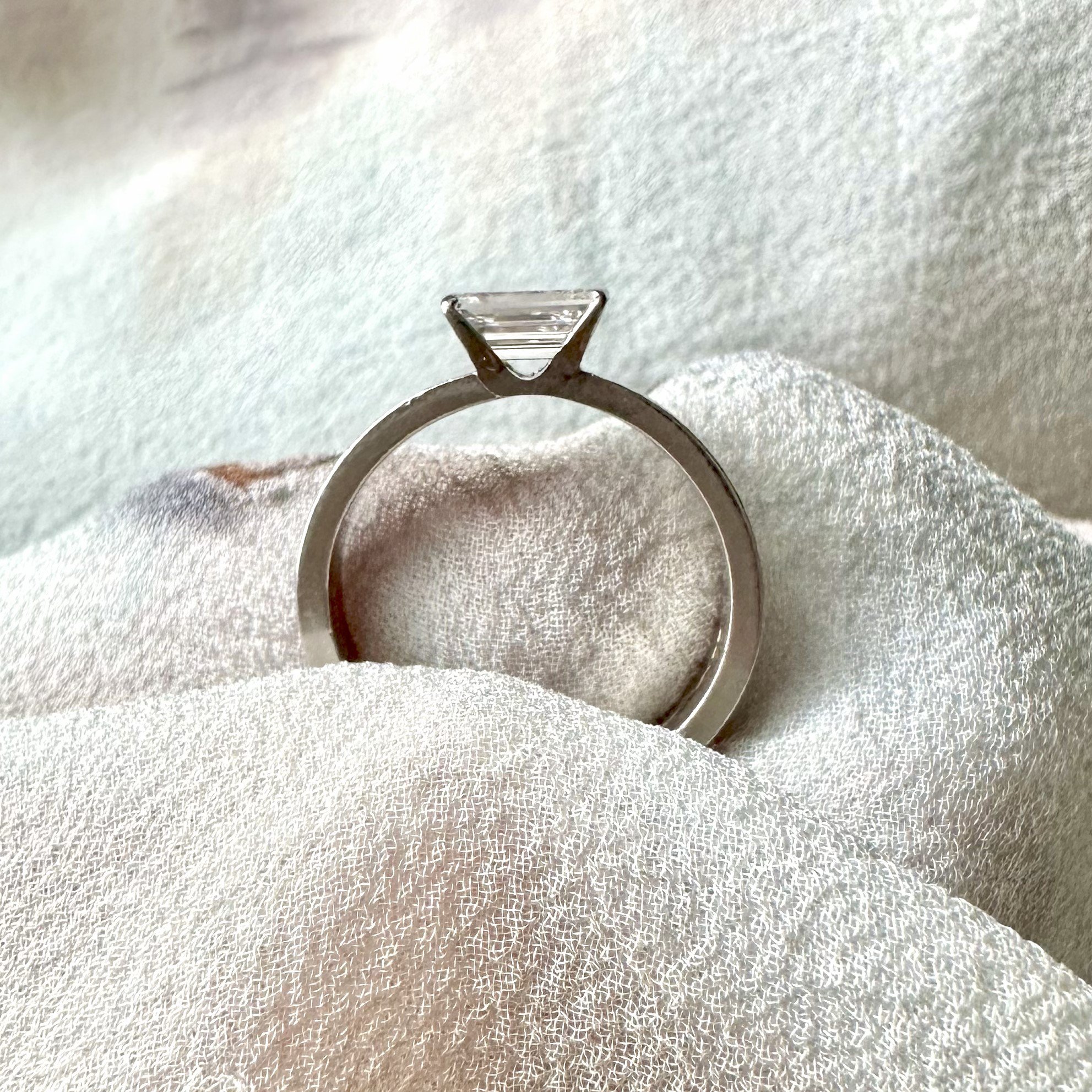 A platinum solitaire ring set with a rectangular cut diamond Approx 0.61cts. Approx weight 6.53 grams, size L.