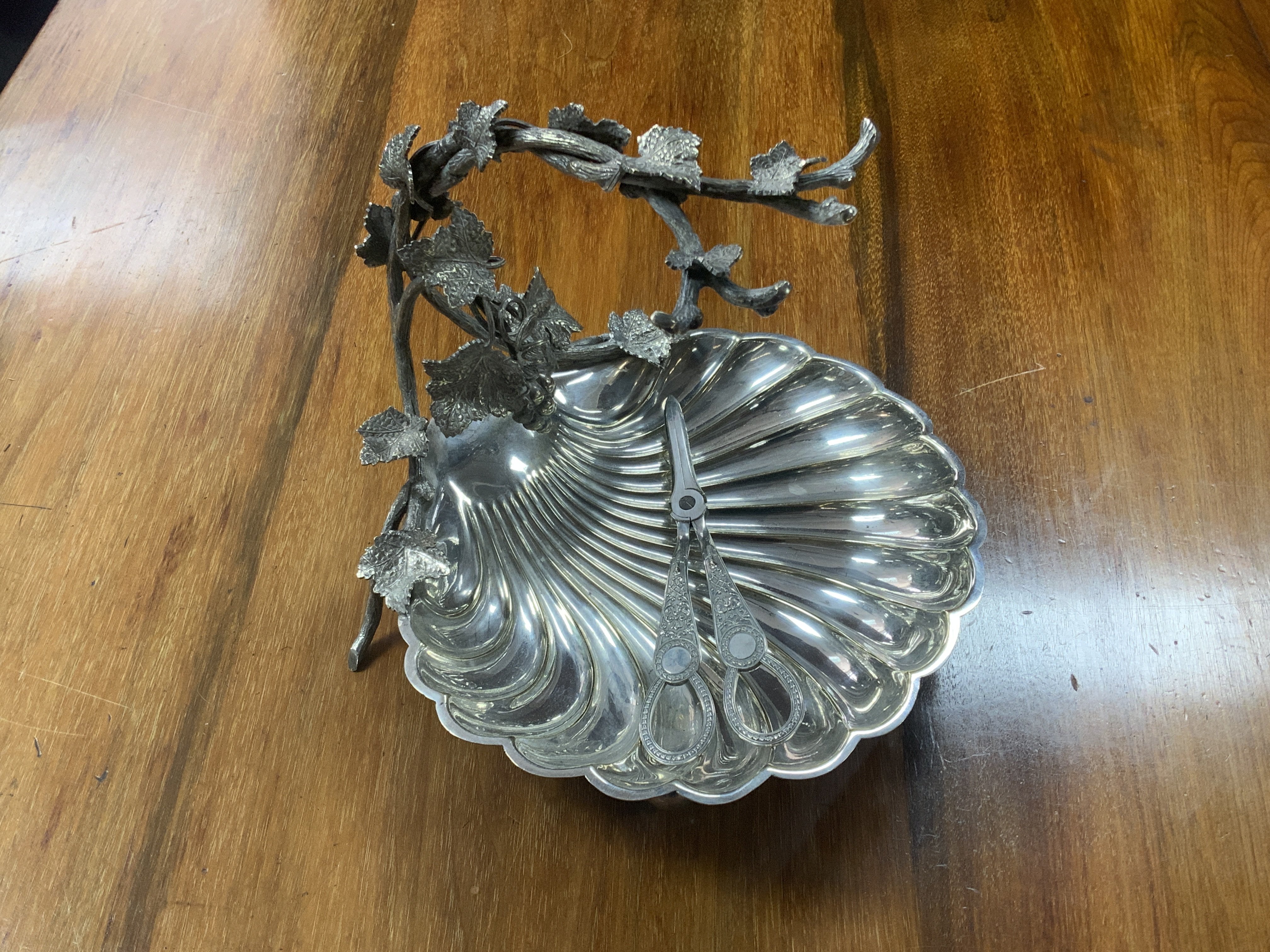 A silver plated grape dish with a grape vine design handle and scalloped shell design bowl together with a paid of gray scissors.