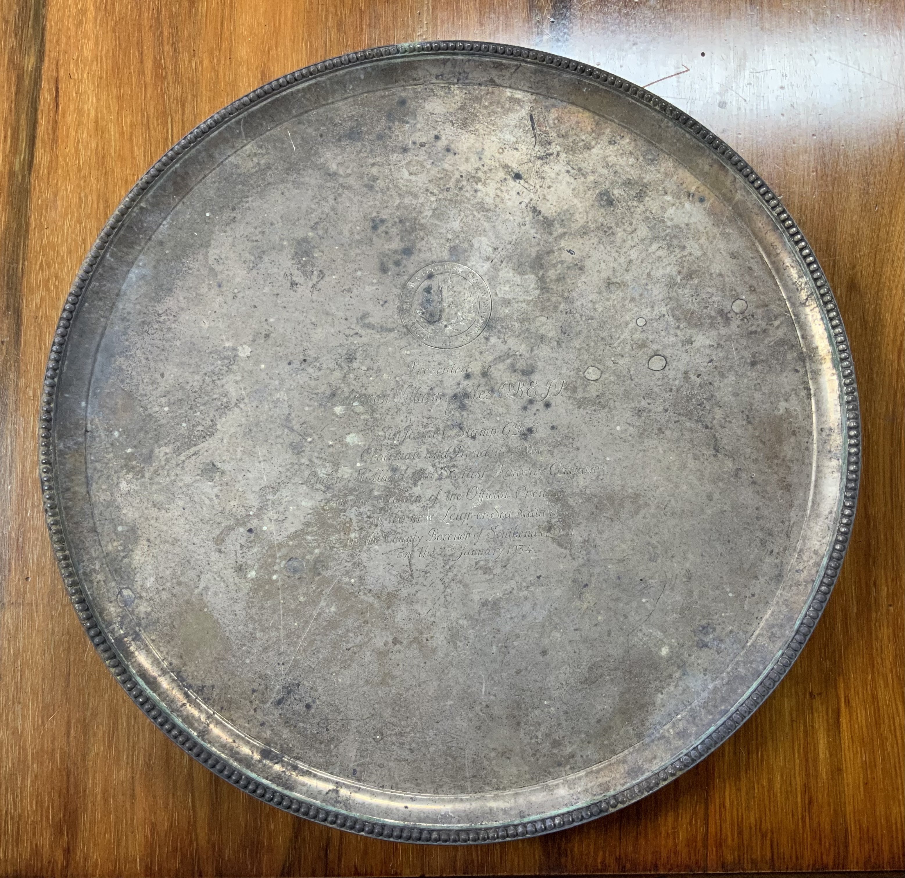 A large hallmarked silver 4 footed serving tray, 1.78kg, Vander & Hedges Tessiers Ltd. (Ref Lot 701, Estate of Alderman L Miles), presented by Sir Josiah C Stamp GBE, London, Midland and Scottish railway company on the opening of Leigh on Sea station. Diameter 38cm x 3.5cm