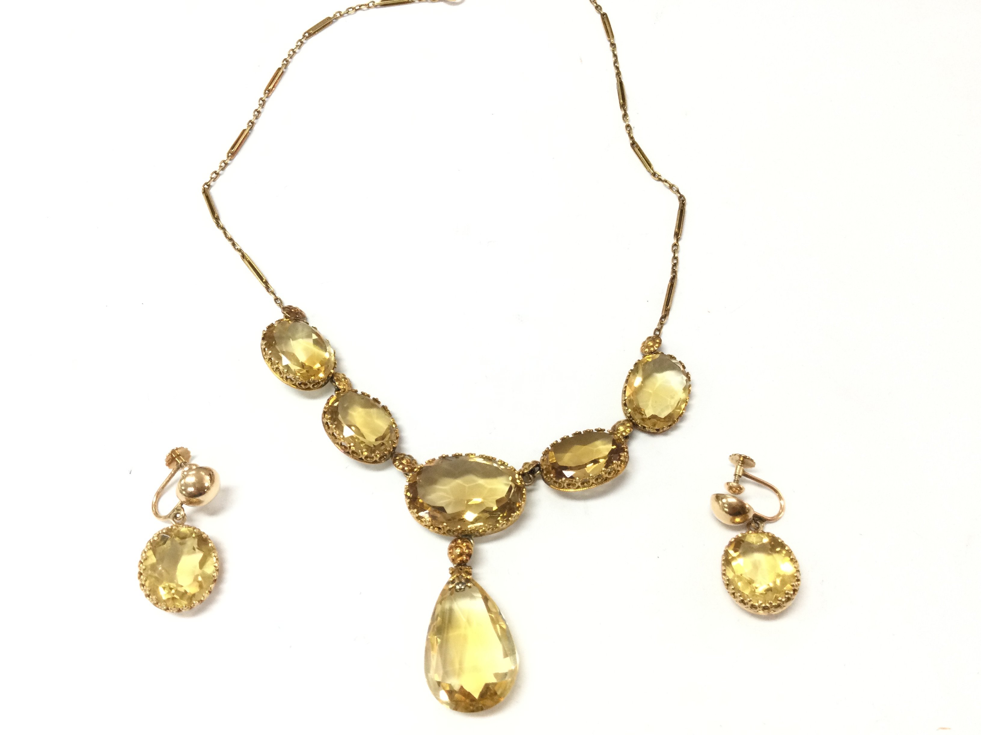 A 14ct gold citrine necklace with 5 oval citrines gold flower links and tear shaped citrine drop. Approx 38cm length and 23.7g with matching 14ct gold oval citrine screw back earrings. 15mm by 12mm and 7.7g Postage B