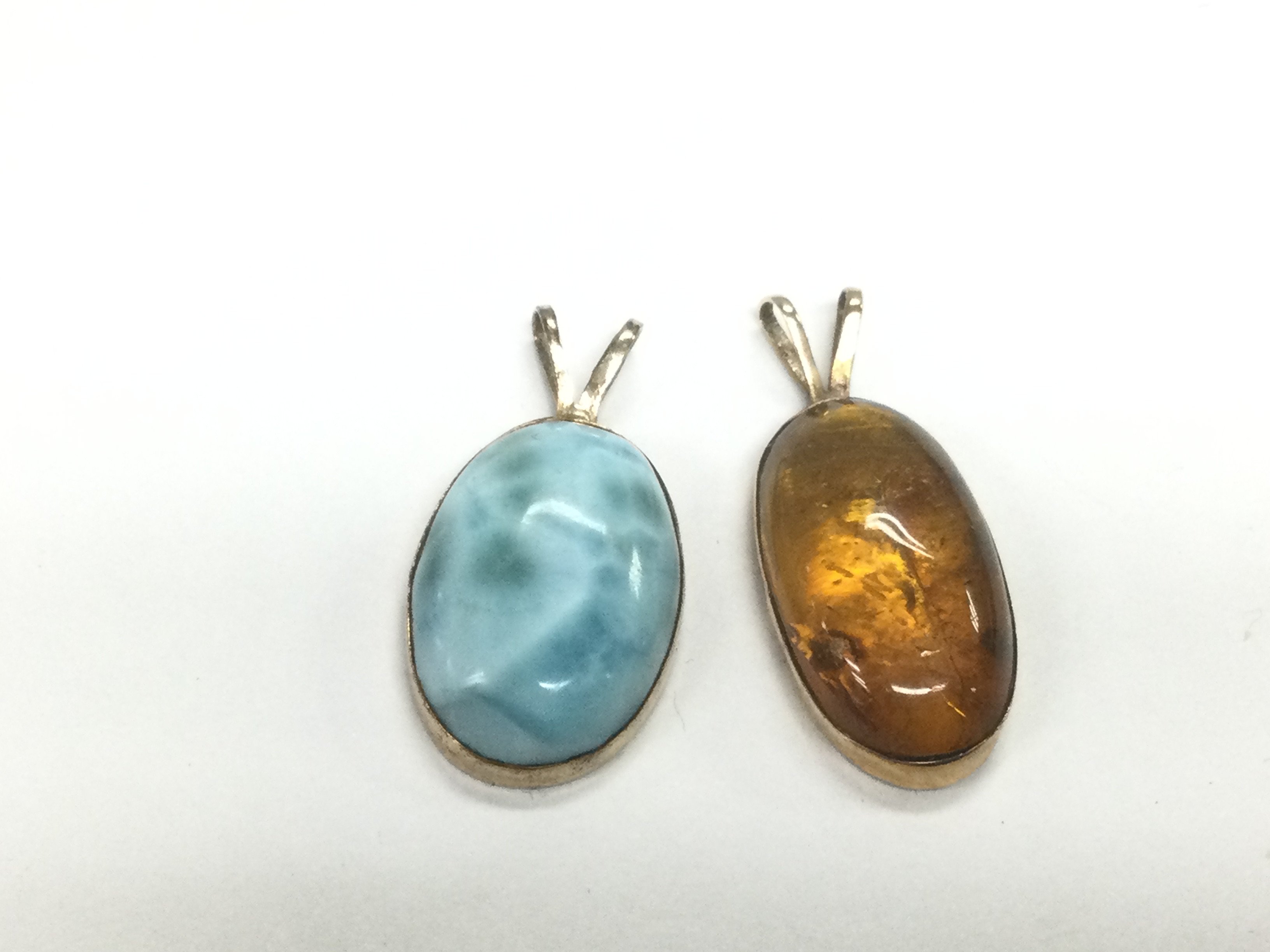 Two 14ct gold pendants comprising one set with amber and one other. Shipping category A.