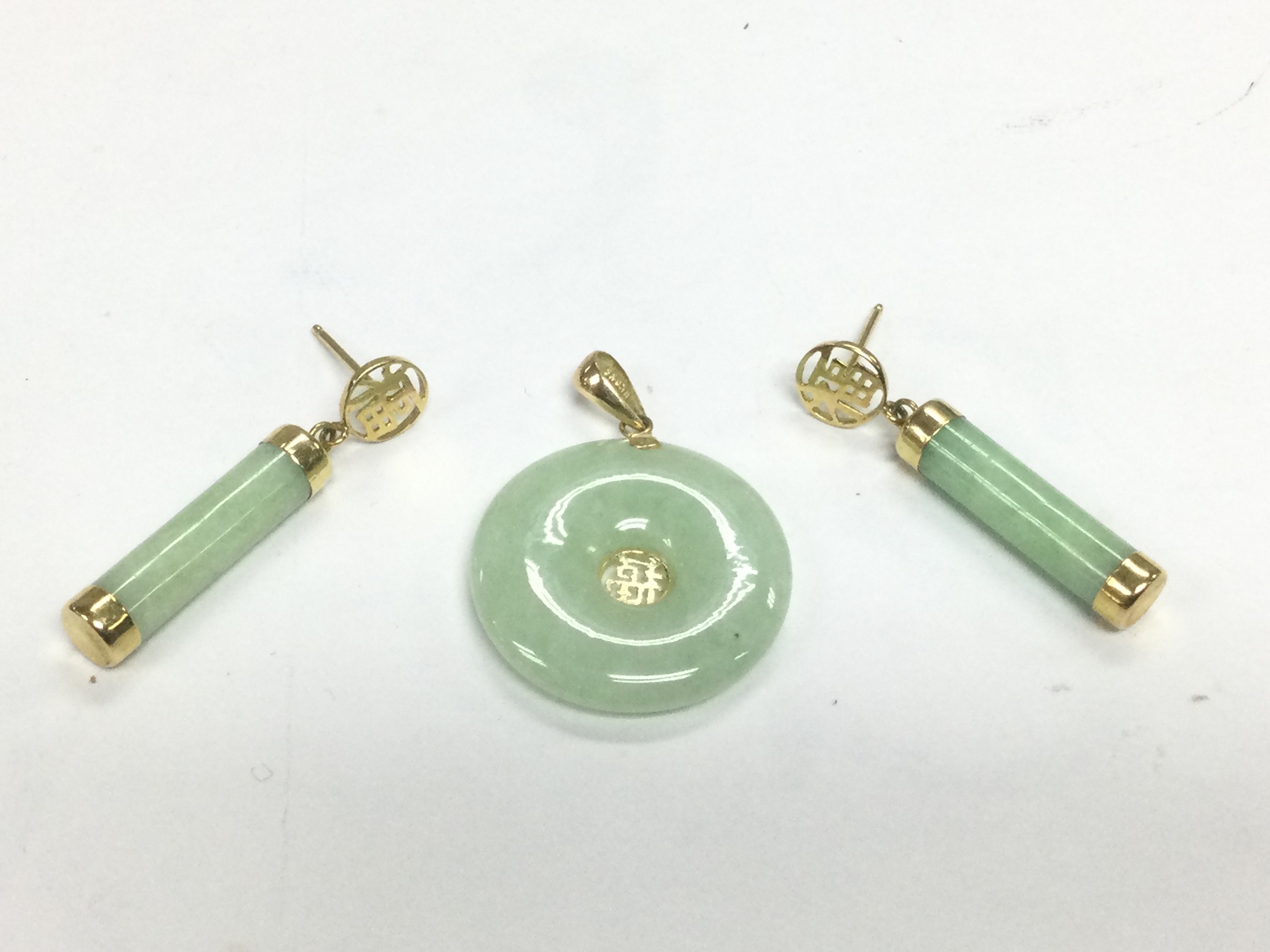 A jade and gold pendant and earrings. Shipping category A.