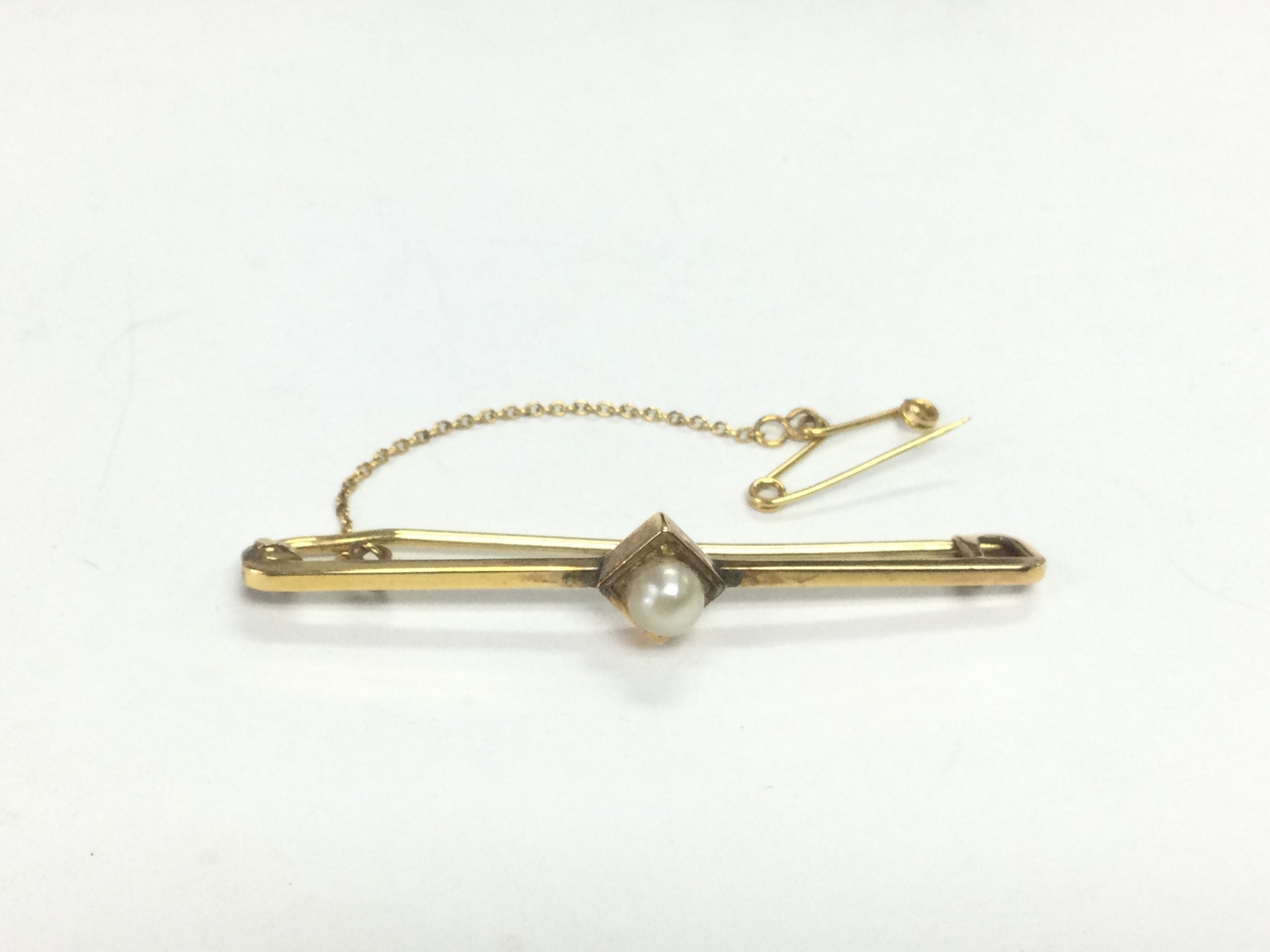 A 9ct gold brooch set with a central seed pearl, approx 2g. Shipping category A.