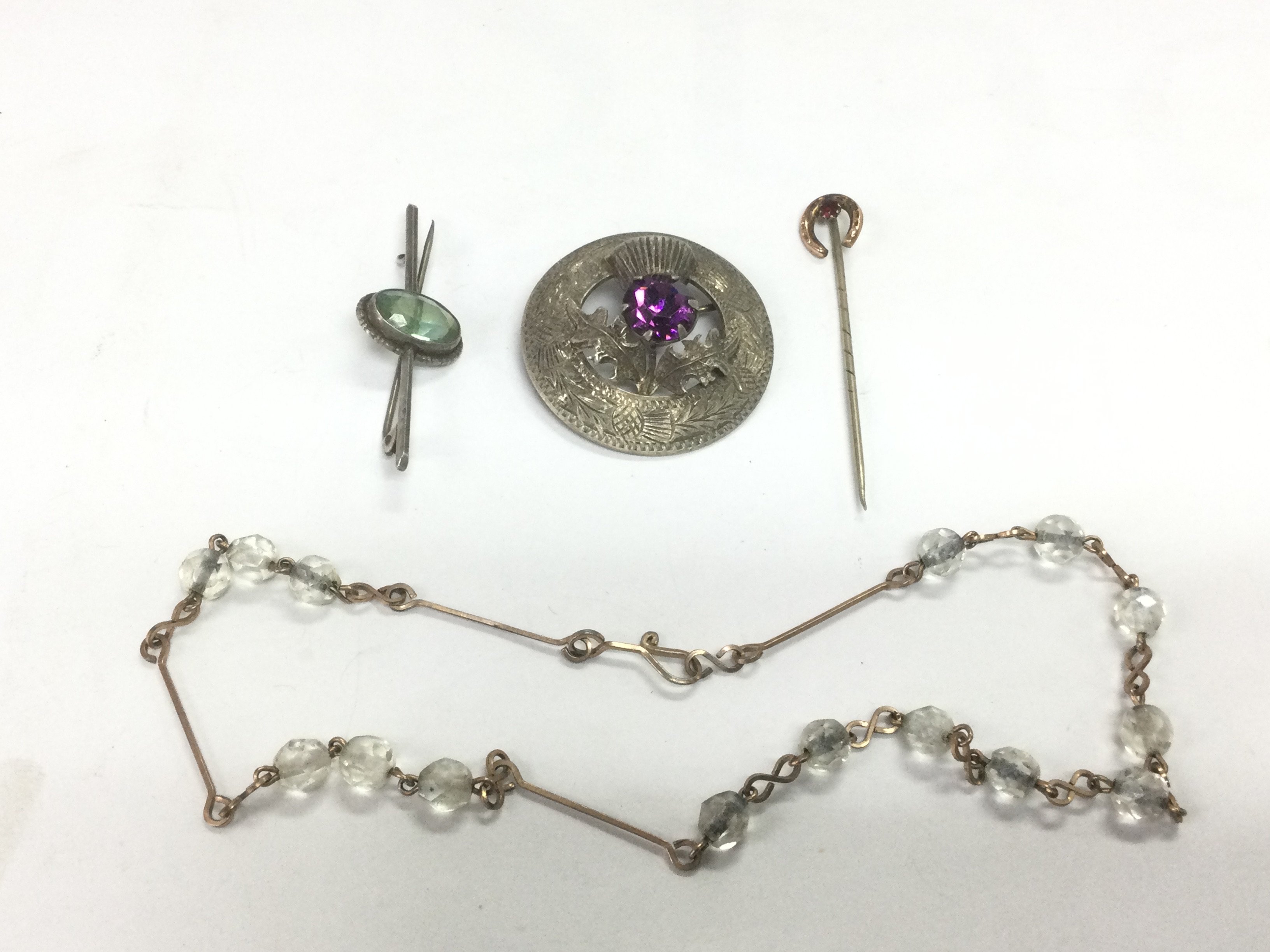 A small mixed lot of jewellery comprising a silver Scottish brooch, child's necklace, stick pin and brooch. Shipping category A.