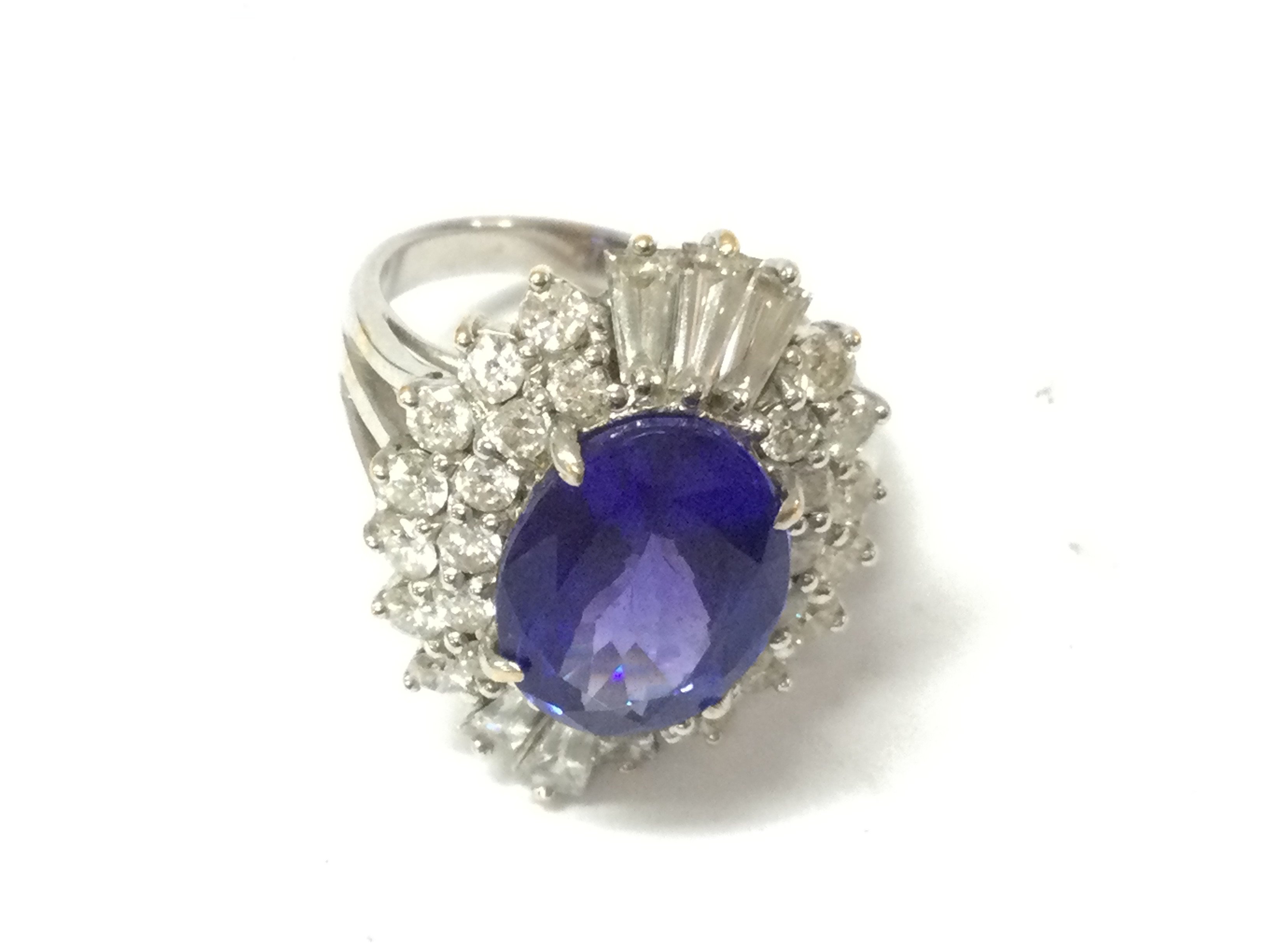 A white gold large oval Tanzanite and diamond ring. Tanzanite carat weight 4.50ct set with 26 round diamonds and 6 tapper baguettes weighing 1.10ct Size N 
with gemologists report