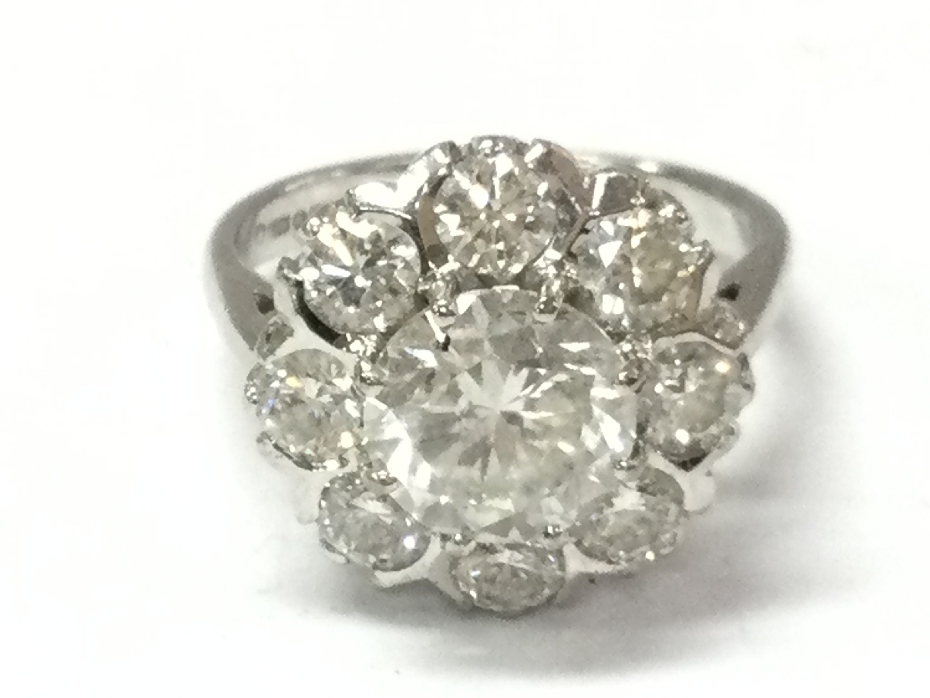 An 18ct white gold diamond cluster ring set with 8 diamonds around the centre weighing 1.50ct. With round brilliant central diamond weight 2.5ct. colour H/I clarity 11 Size P.
with gemologists report