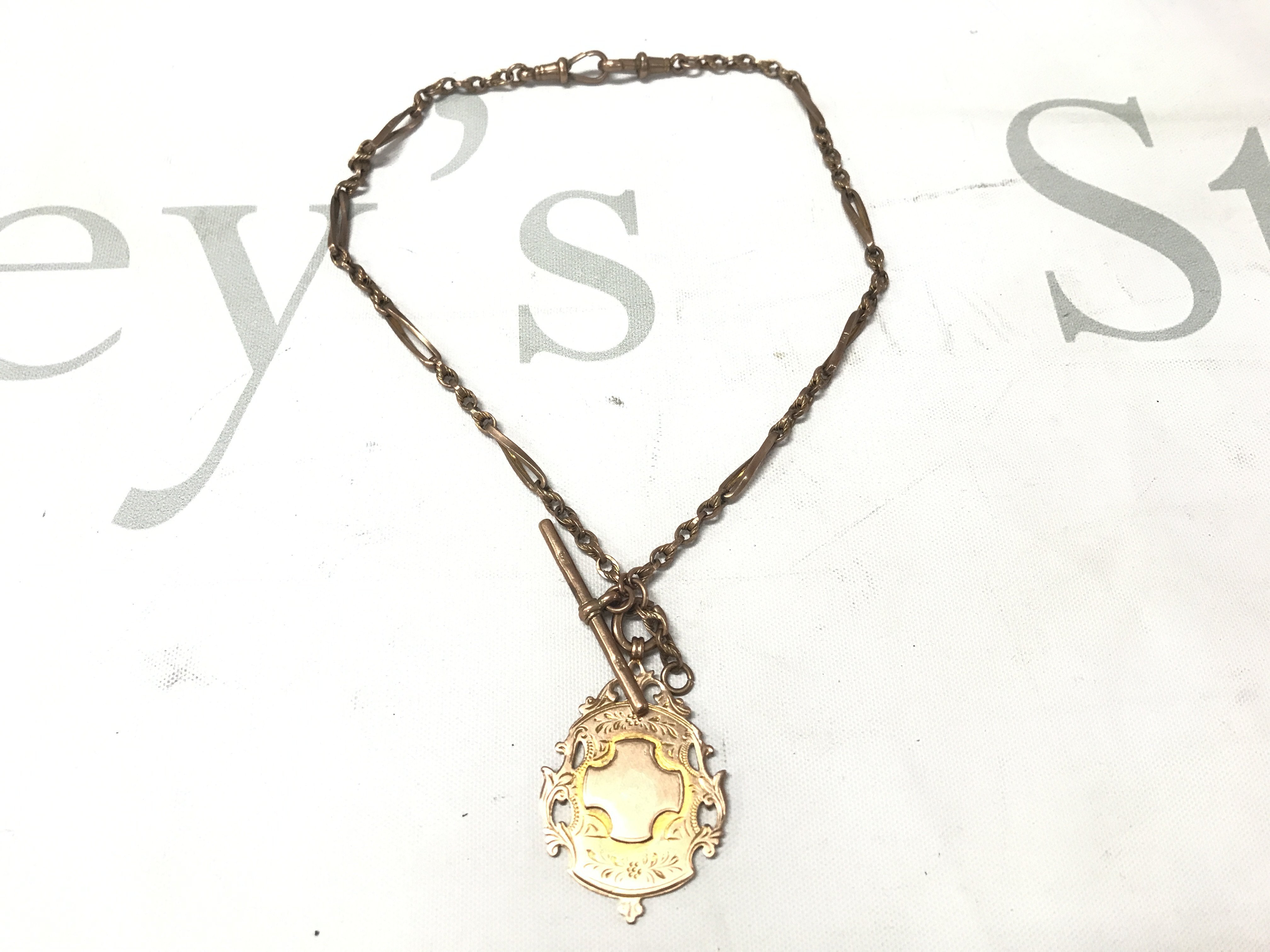 A 9ct gold watch chain with a 9ct gold pendant attached. 16.79g Postage A