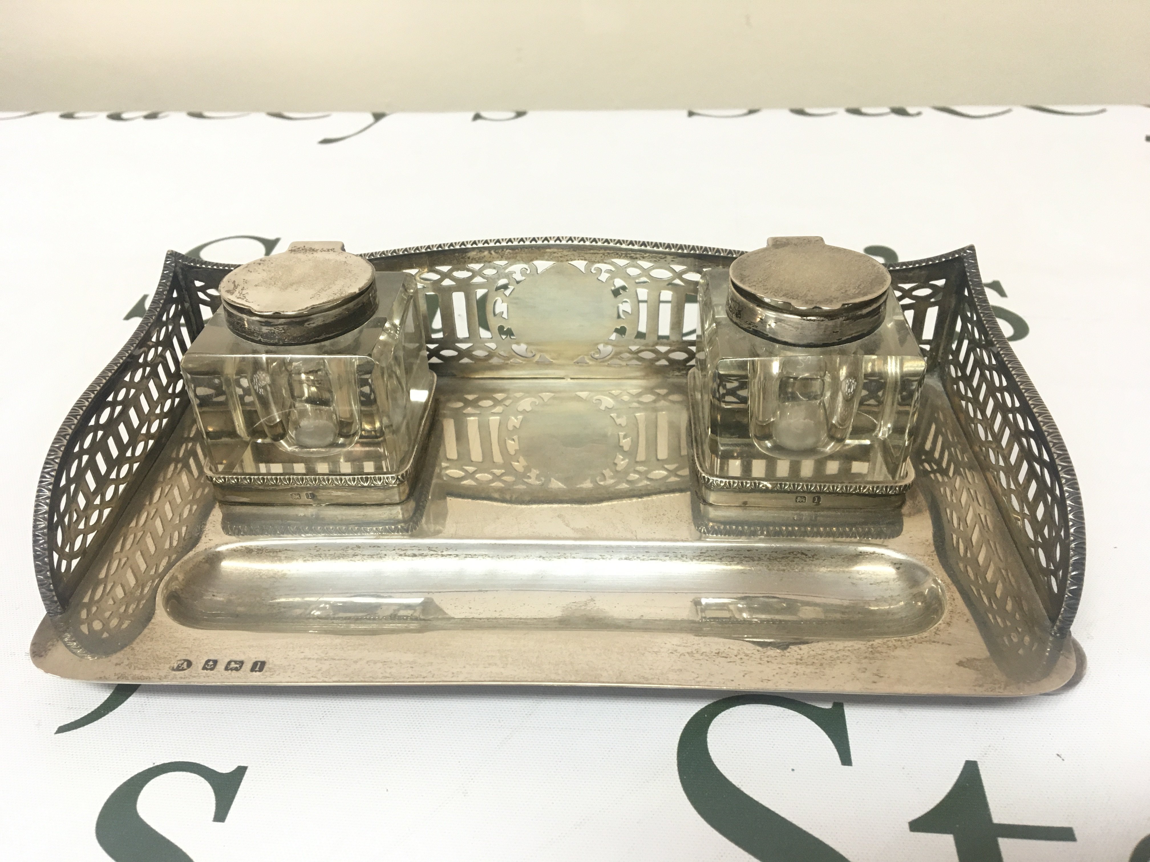 A Silver pen tray with a raised gallery and glass inkwells. On bun feet Birmingham hallmarks good condition.