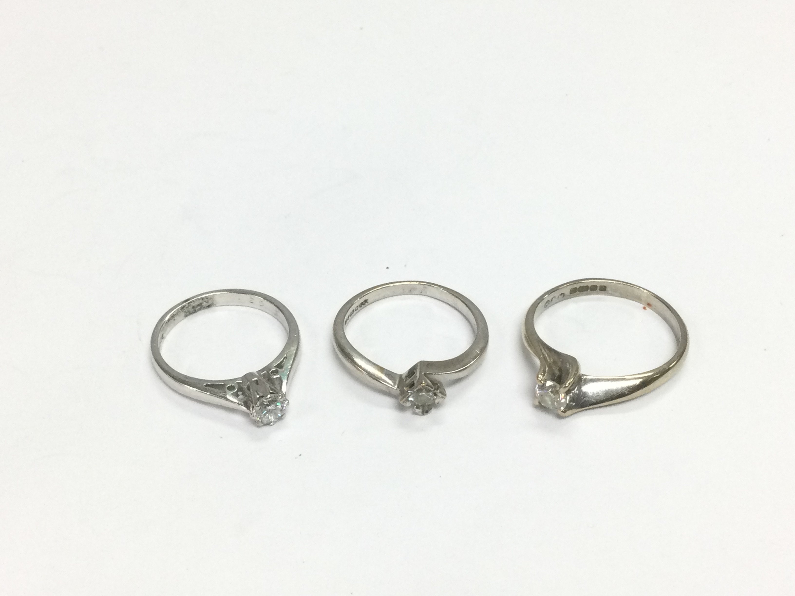 Three 18ct white gold diamond solitaire rings, approx sizes H and M. Total approx 7.7g. Shipping category A.