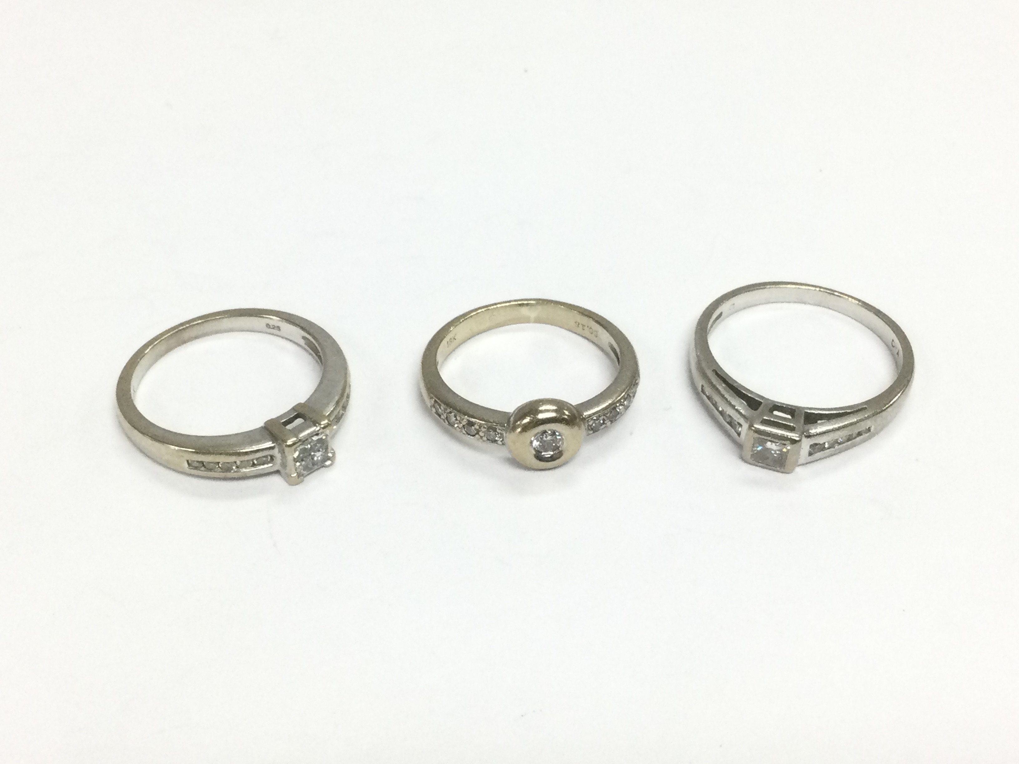 Three 18ct white gold solitaire diamond rings set with further diamonds to the shoulders, approx sizes L, N and O. Total approx 11g. Shipping category A.