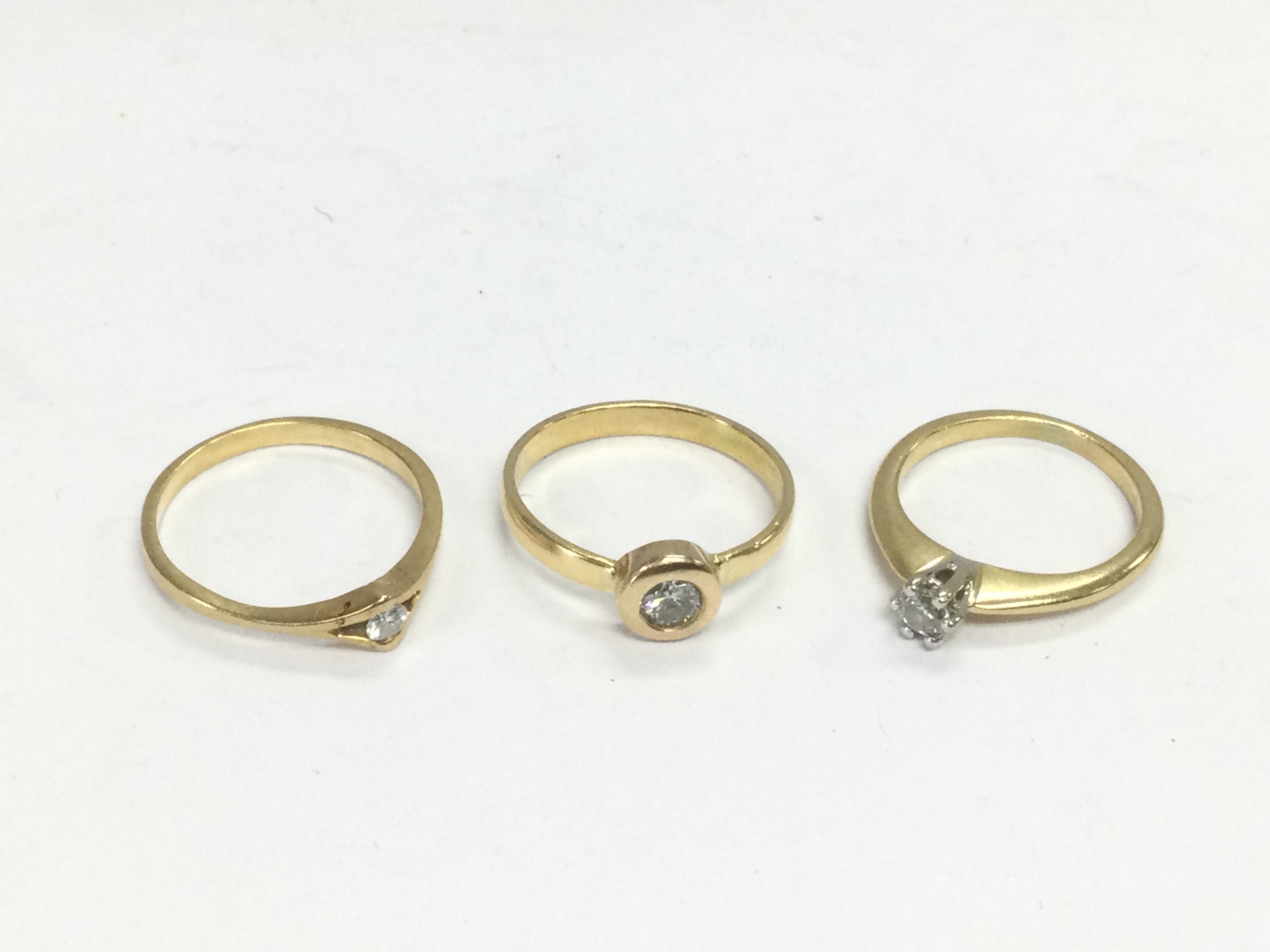 Three unmarked gold diamond solitaire rings, approx sizes M, L-M and I-J. Total approx 6.9g. Shipping category A.