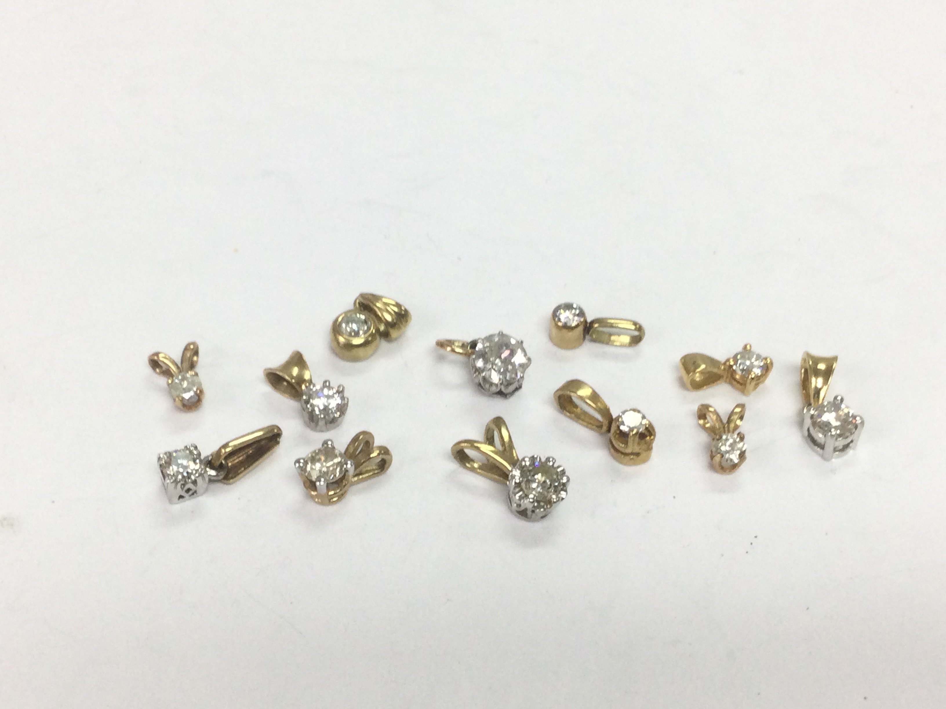 Twelve gold solitaire diamond pendants, total approx 4.6g. Shipping category A.