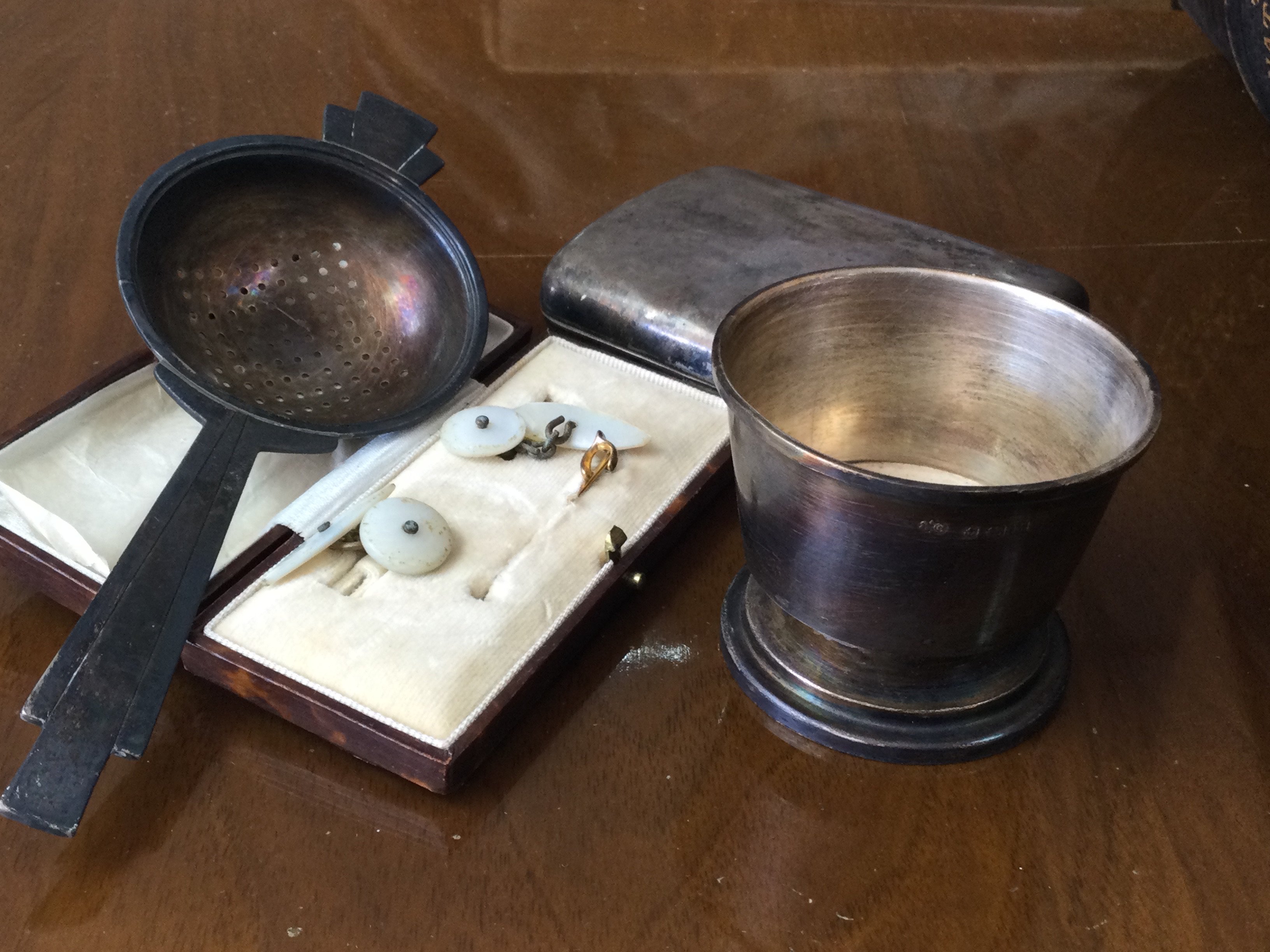 A silver cigarette case and tea strainer