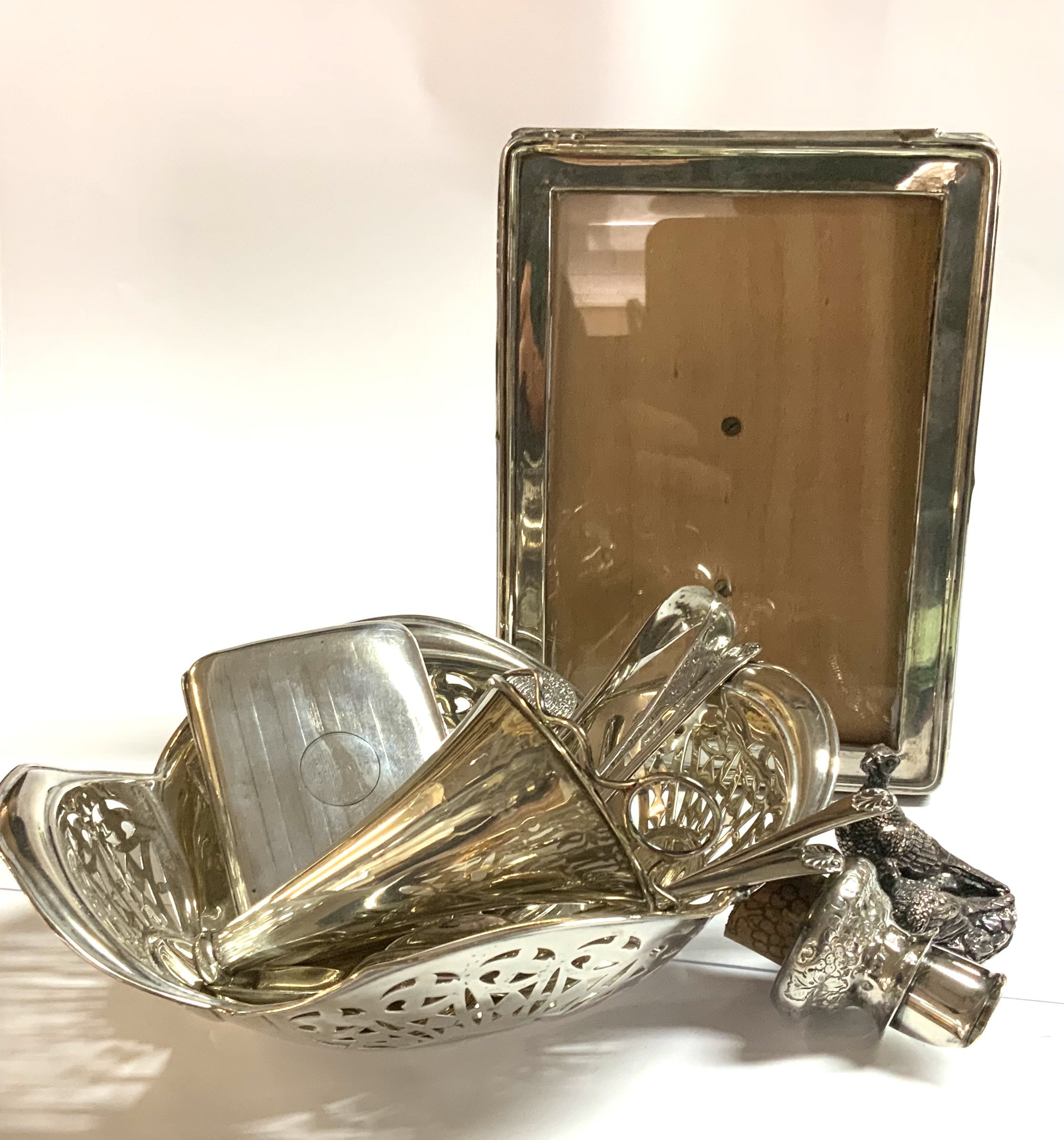 A hallmarked silver basket, Silver photo frame, Hallmarked silver wine bottle pourer, Silver overlaid pheasant, cutlery.