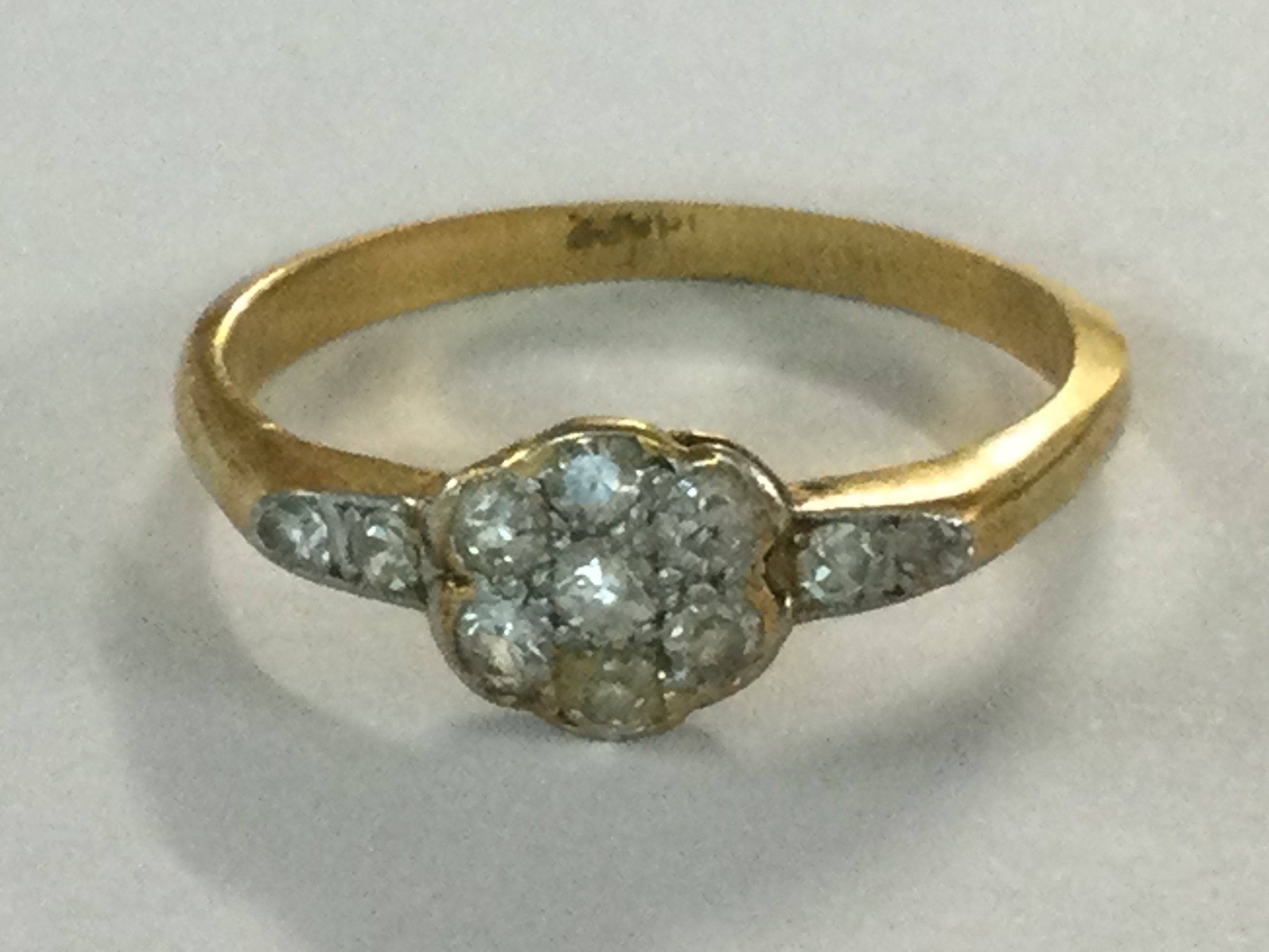 A gold ring of floral design inset with diamond chips