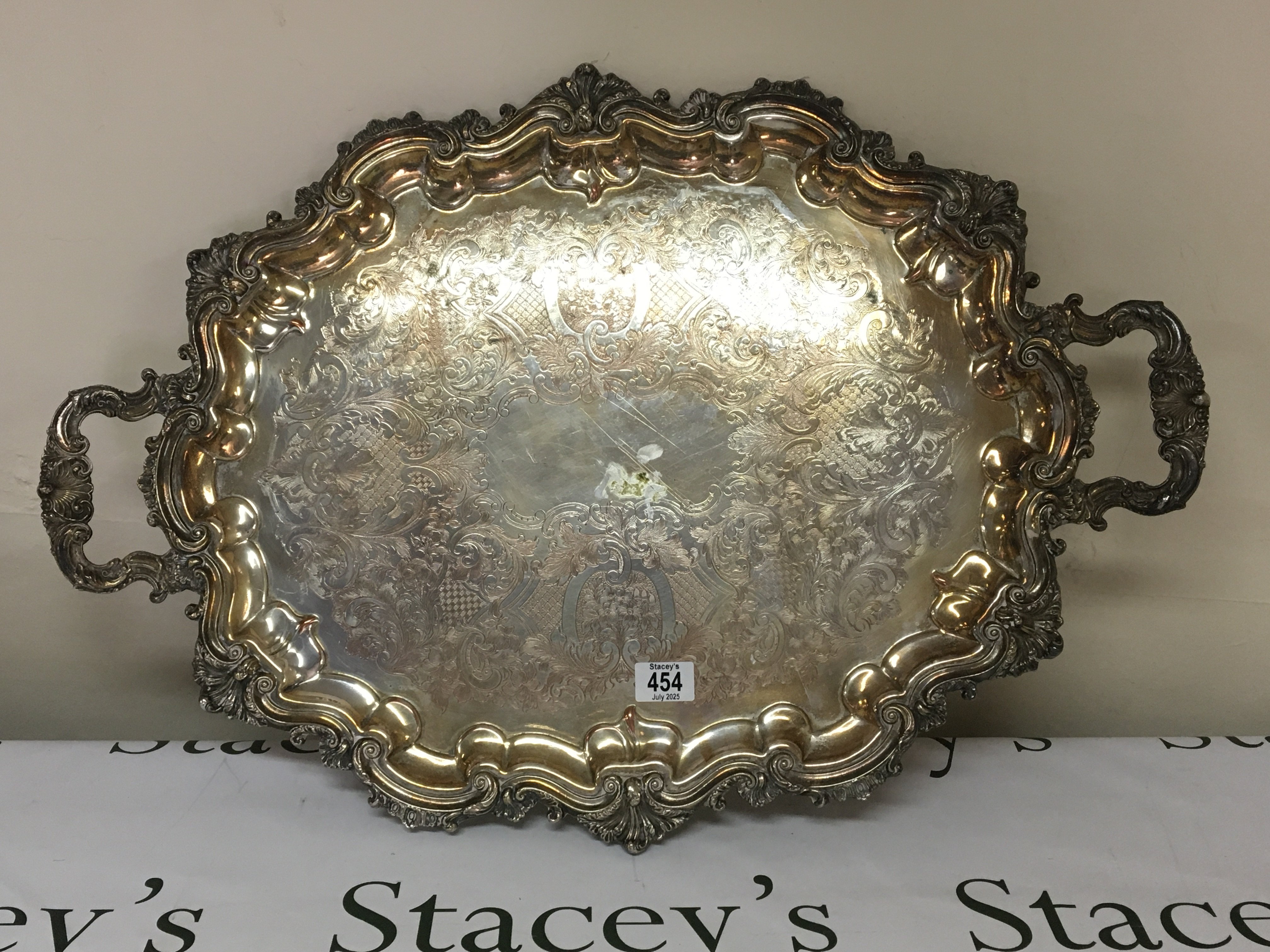 A large silver plated tray with a shaped edge and carrying handles diameter 75cm