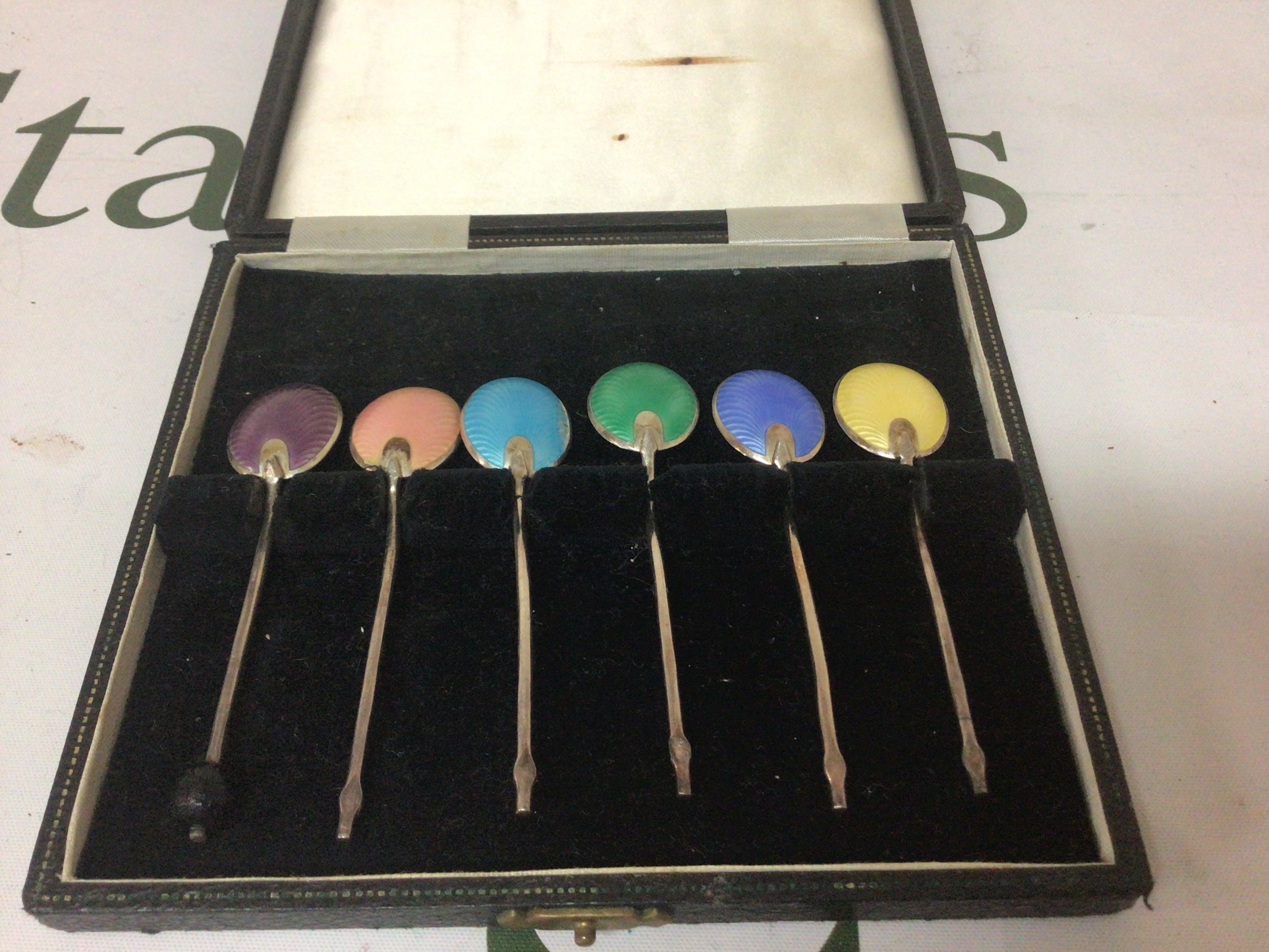 A cased set of silver and enamel coffee spoons.
