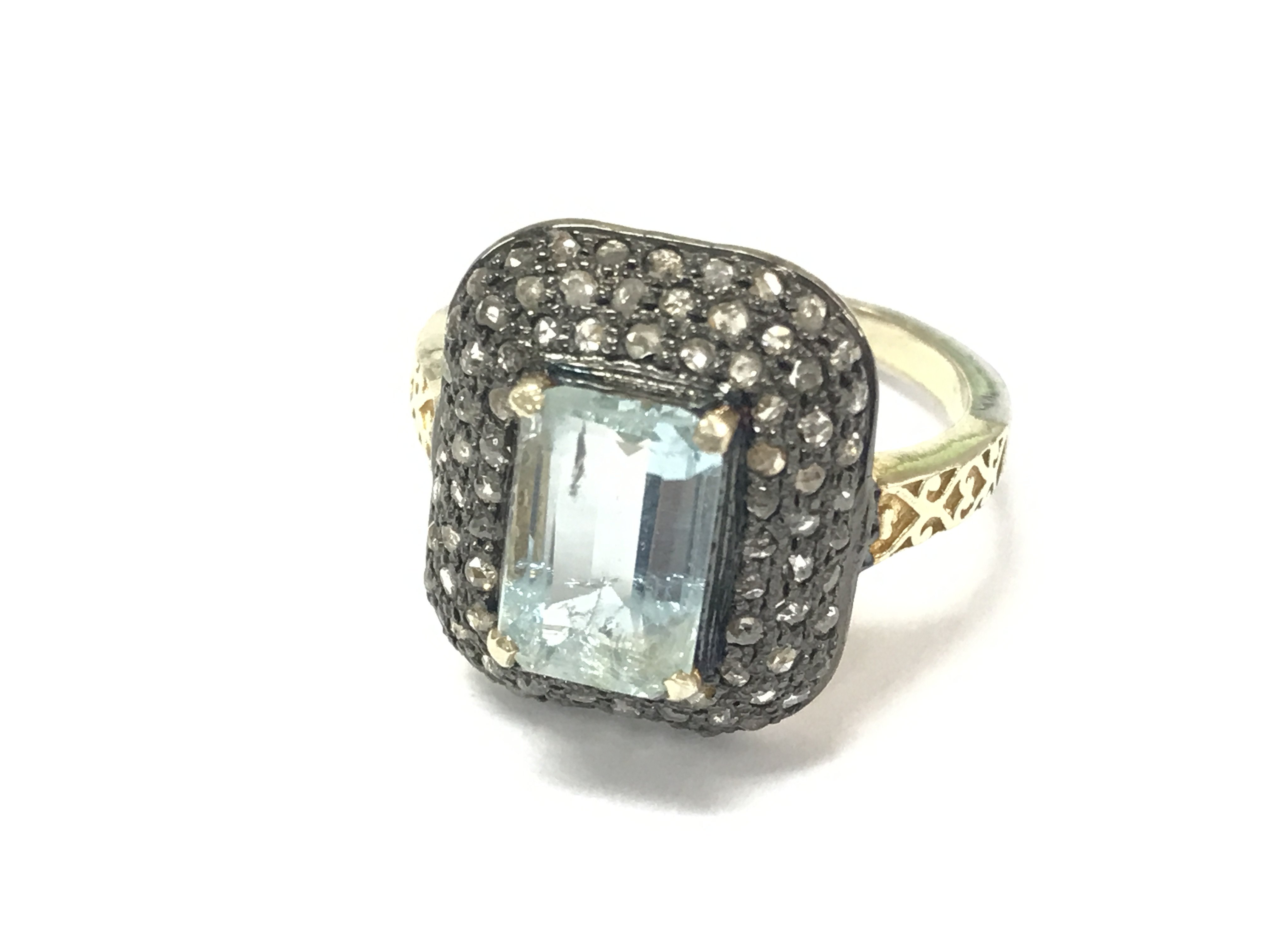 A vintage style aquamarine and diamond ring with hand carved design in silver gilt. Emerald cut aquamarine 2.10ct and diamonds 0.72ct. Size P