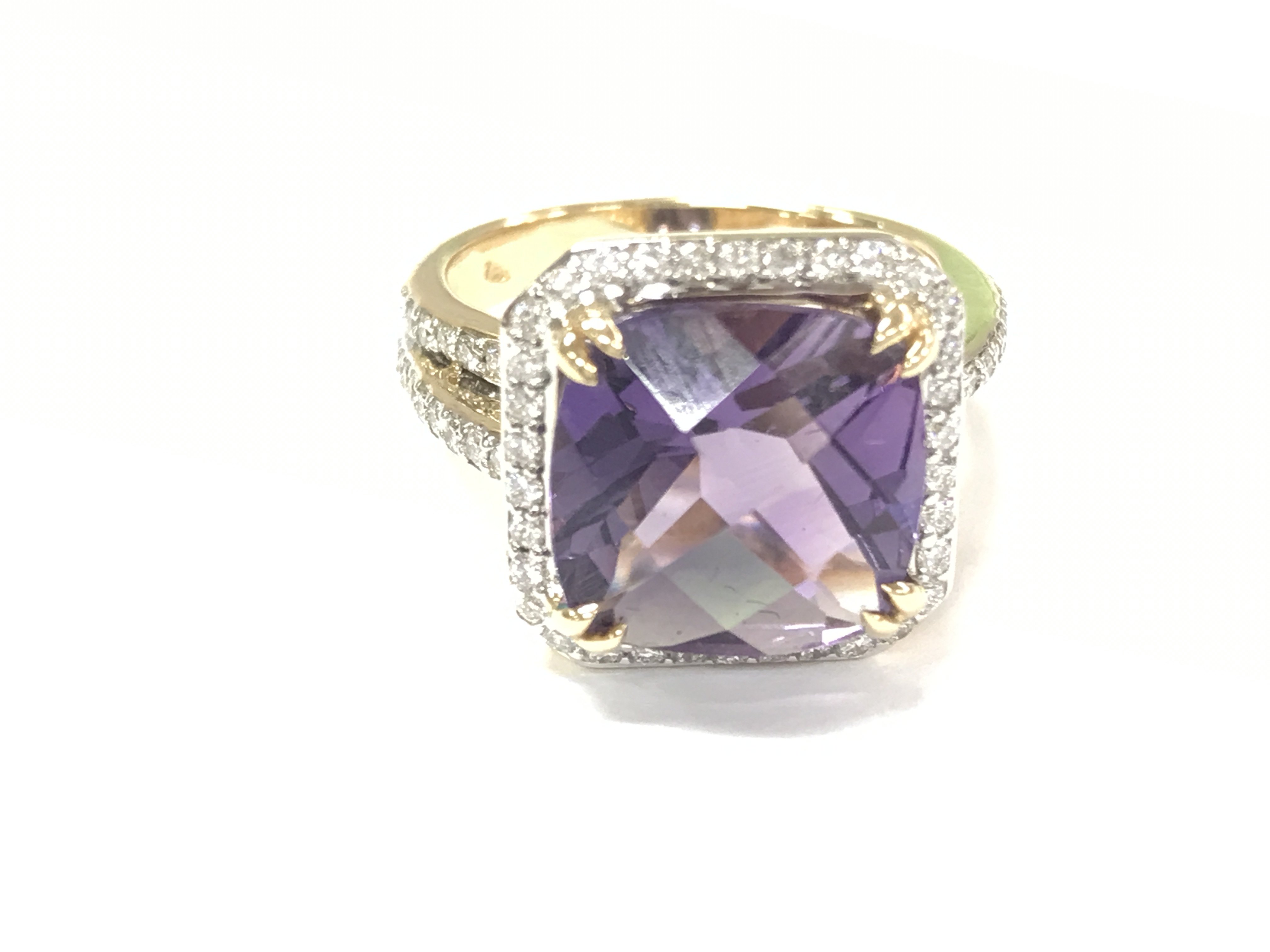 An 18ct gold ring set with a large checkerboard cushion cut amethyst surrounded by diamonds and diamond split shoulders. Amethyst 4.90ct and diamonds 0.47ct approximately. Size M 1/2.