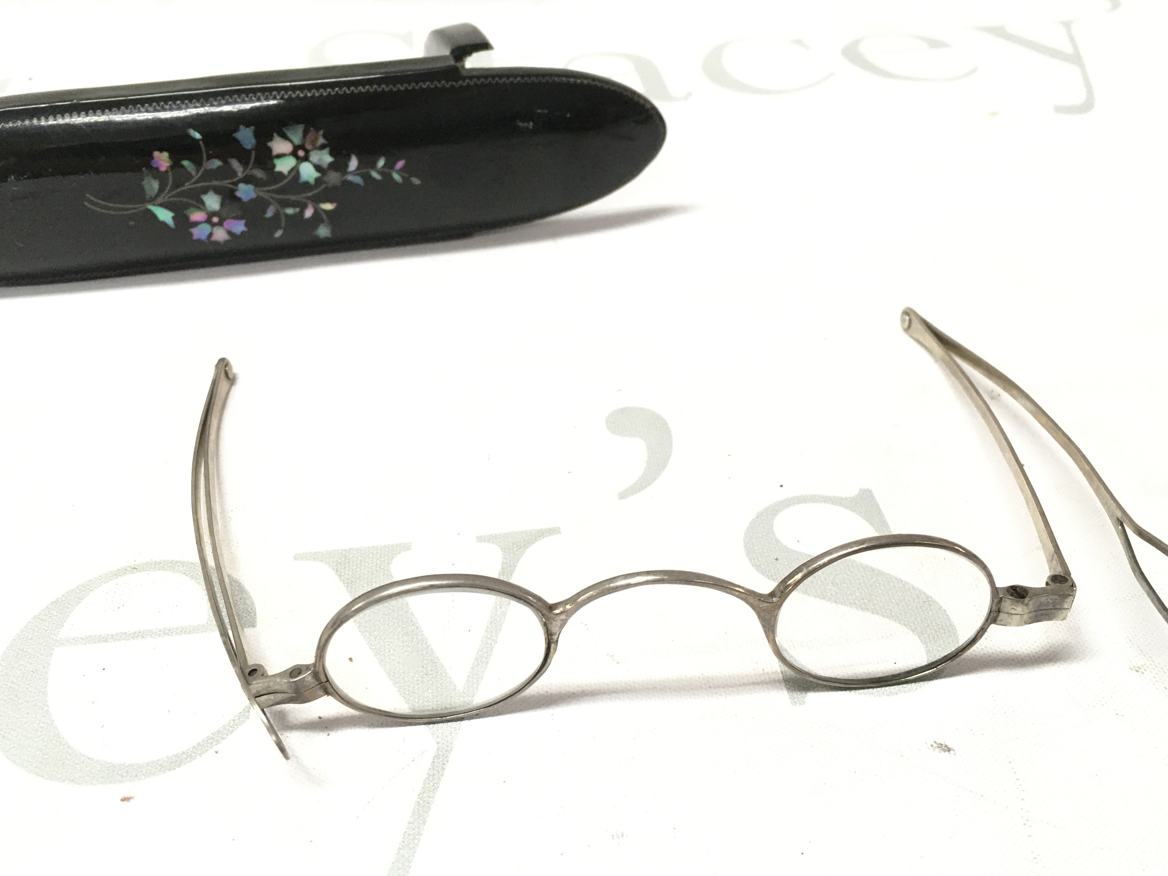 A pair of silver spectacles in a case.