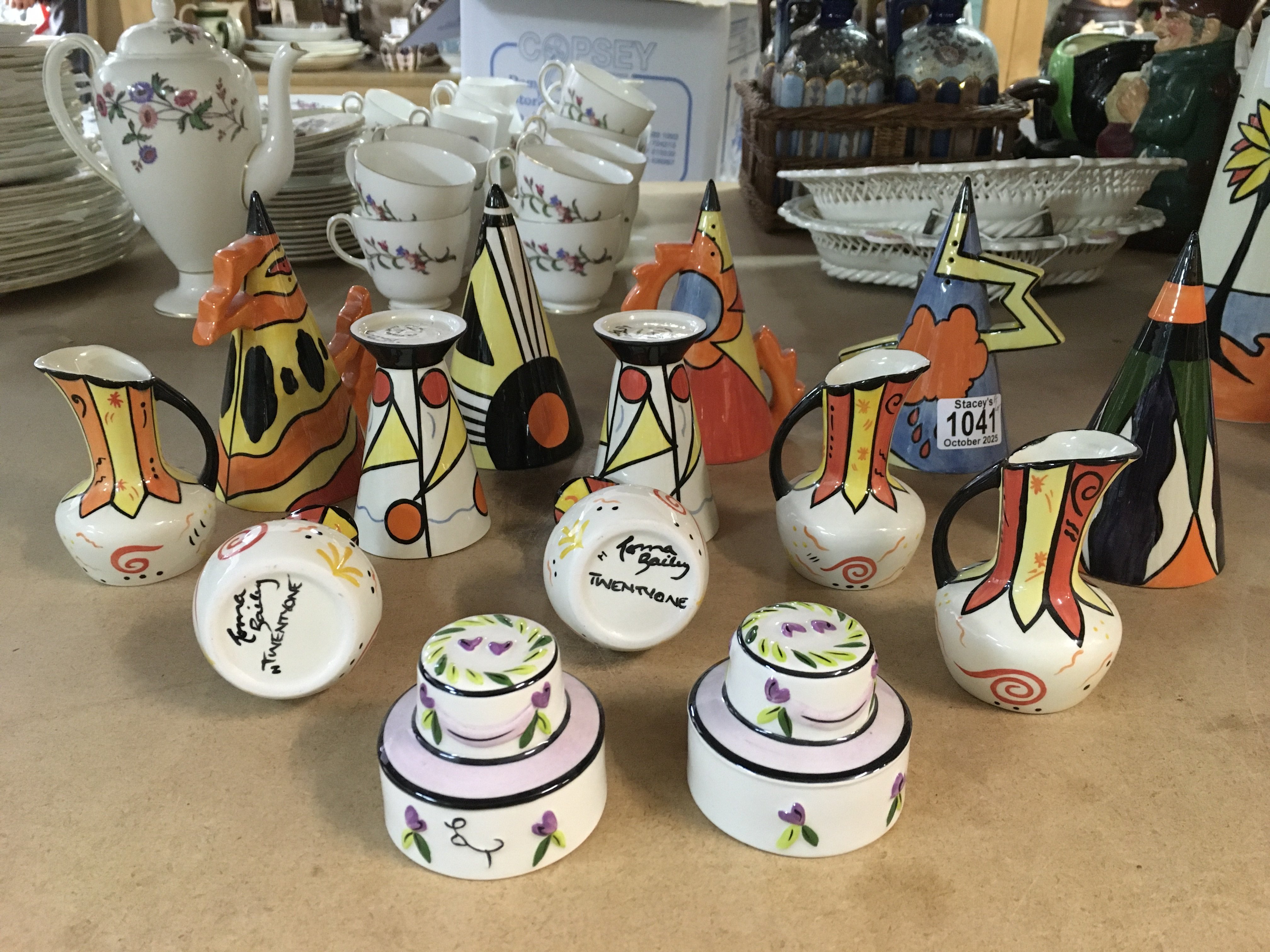 A collection of Lorna Bailey pottery, including small jugs with "Twentyone" to the bases, miniature vases with, miniature cakes and Fire, sunset and Thunderbolt sugar shakers