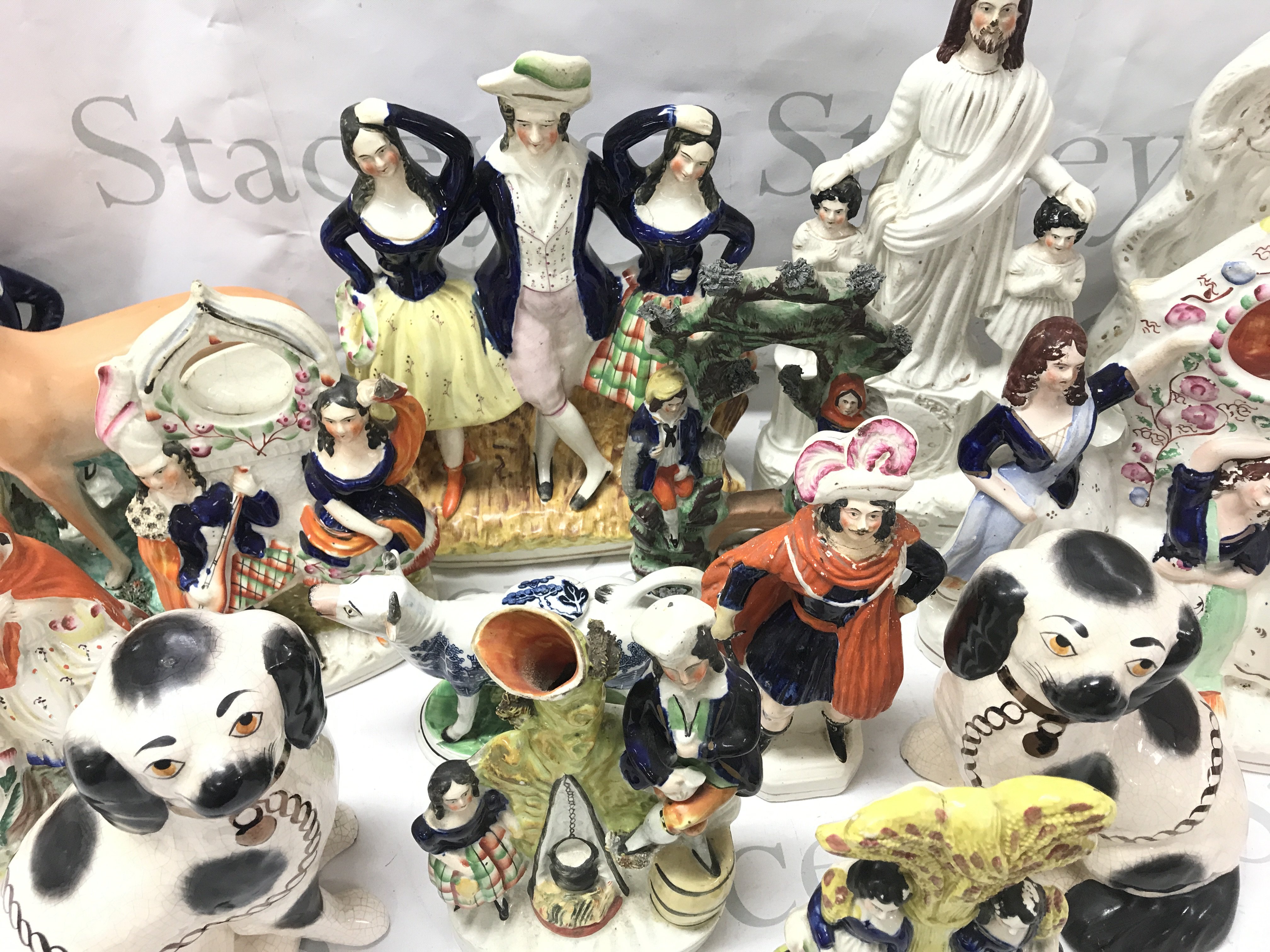 A large collection of Staffordshire figures including Courting couple, dog, cream cow, clock figure groups without clock movements. This lot cannot be posted