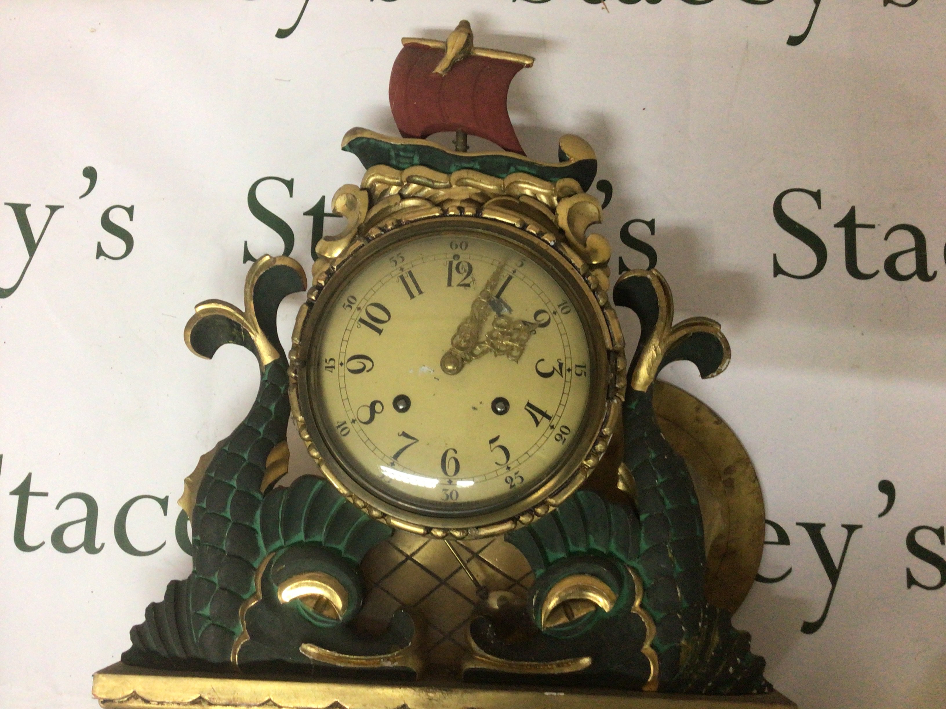 A Swedish wall clock gilt wood Gesso and painted. In the form stylised dolphins the case top surmounted with a sailing ship. With pendulum Hight 60cm- NO RESERVE