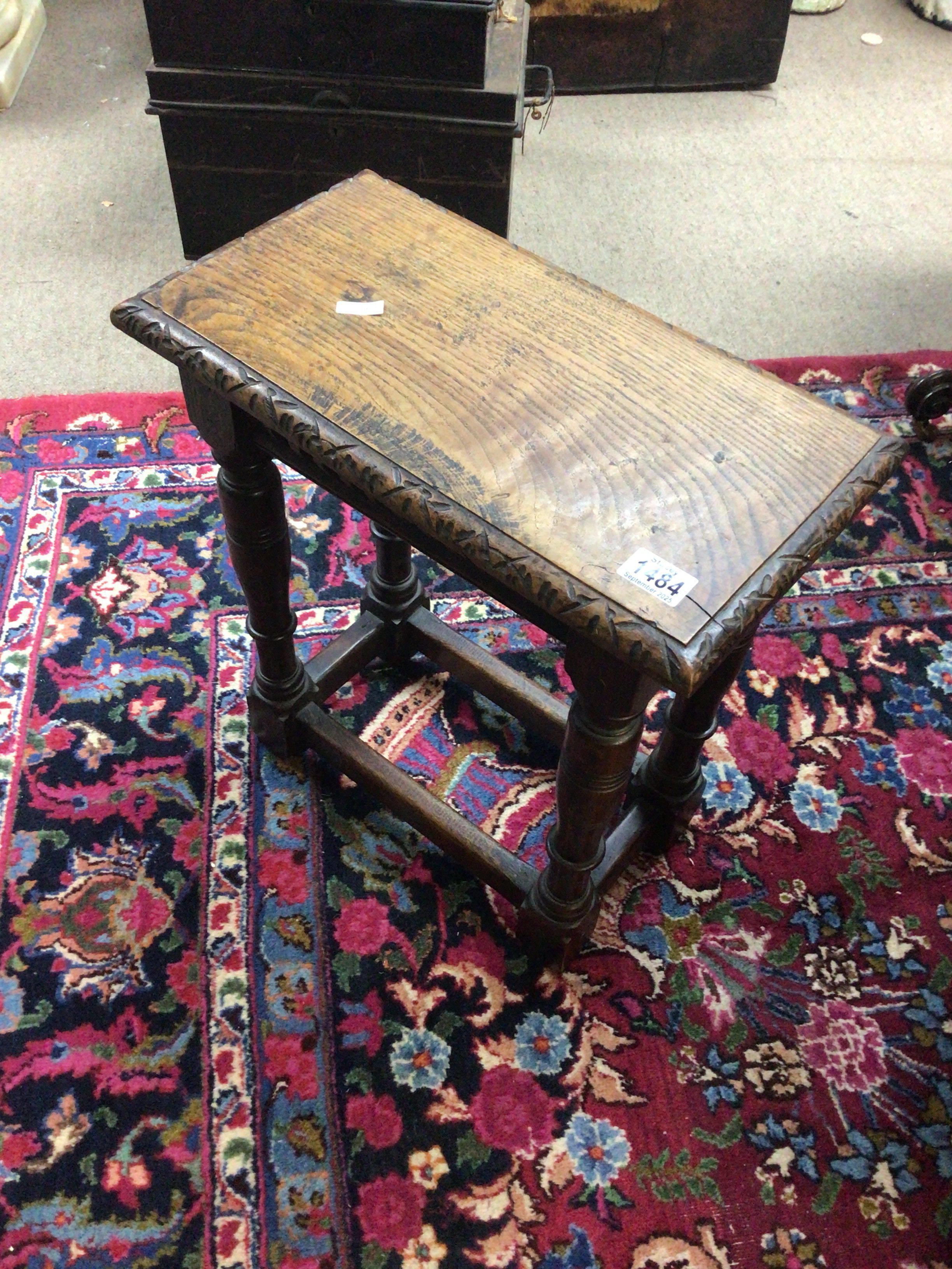 An Early 19th century English Vernacular carved oak coffin stool the top with carved edge on turned legs united by stretchers. Hight 51cm- NO RESERVE