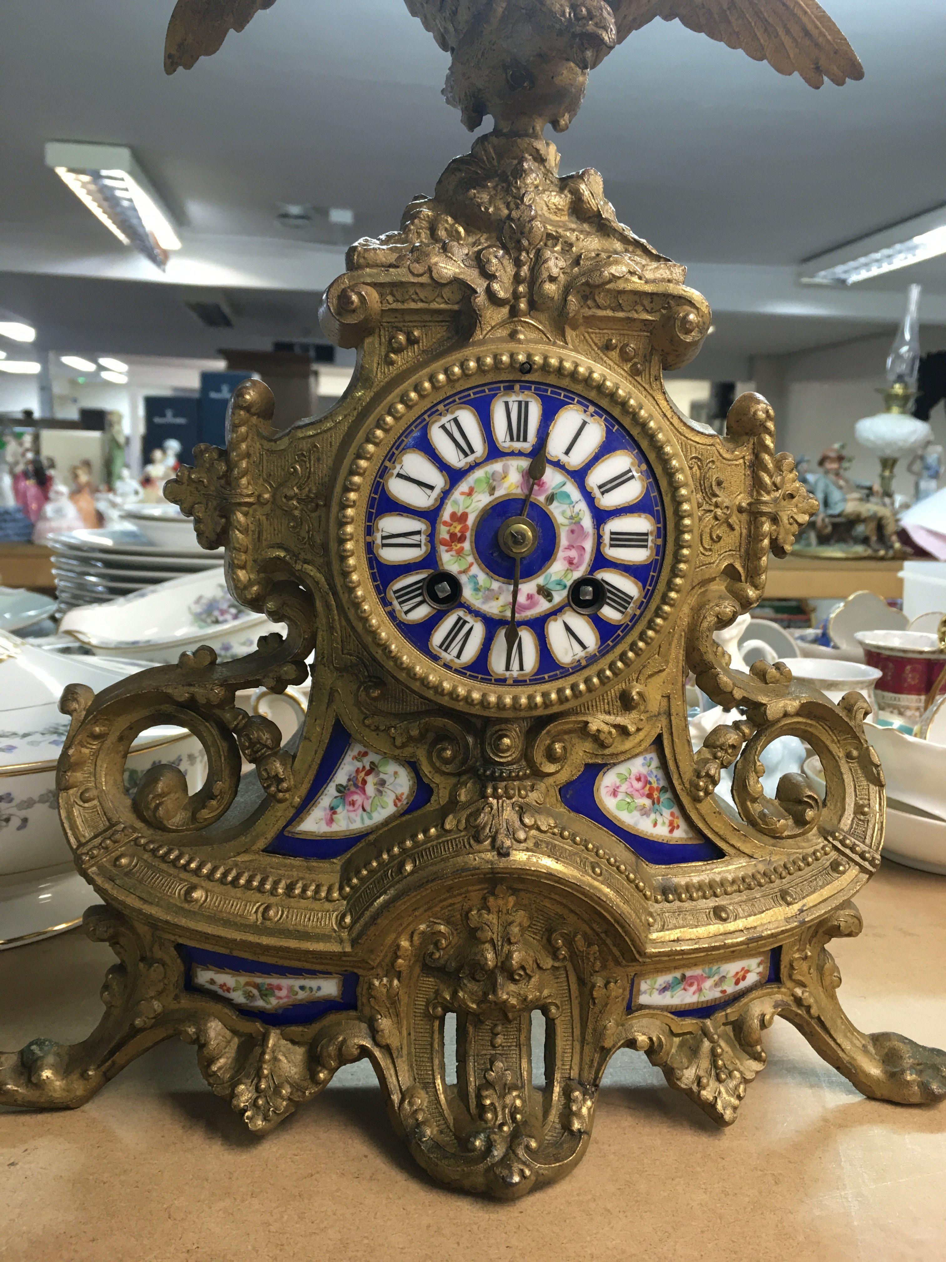 A french gilt clock the blue floral dial with Roman numerals above a flying eagle.
