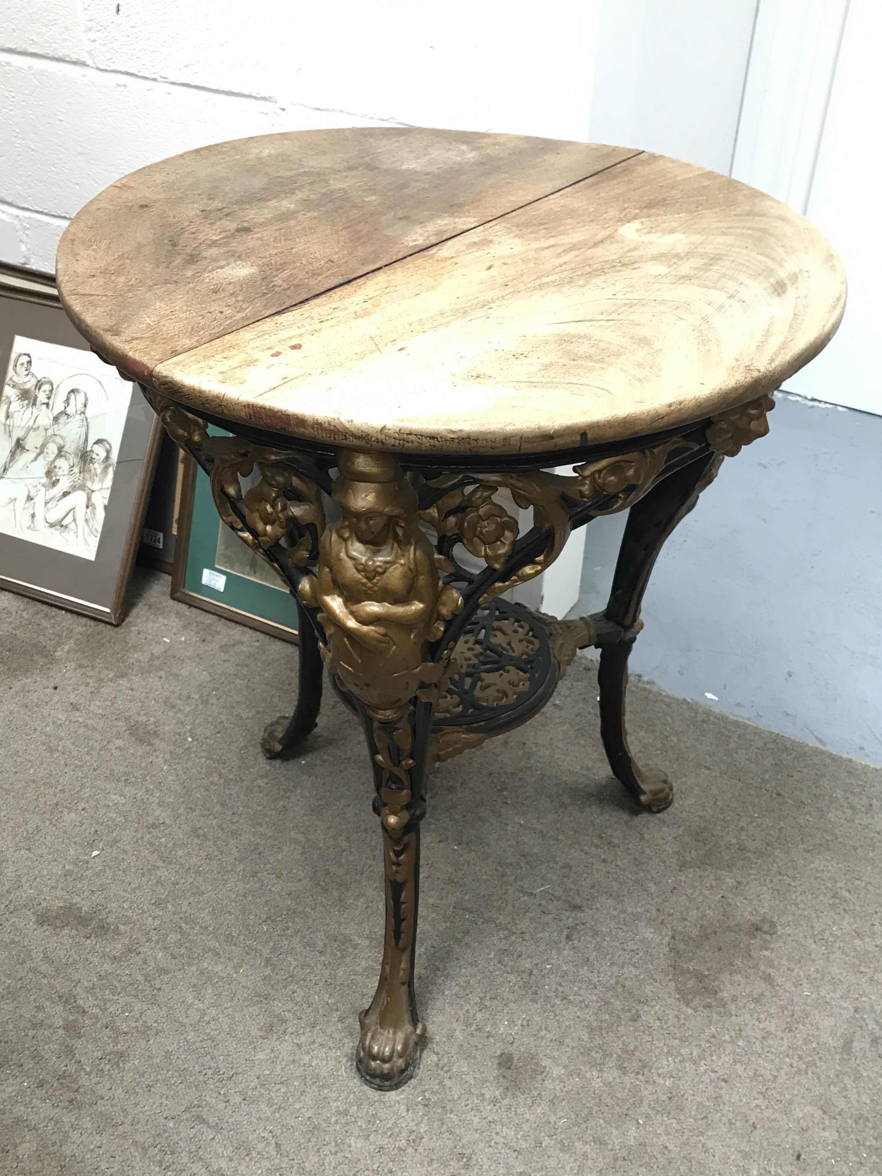 A Victorian cast iron pub table with lion paw feet, lion head, floral decoration and figures.