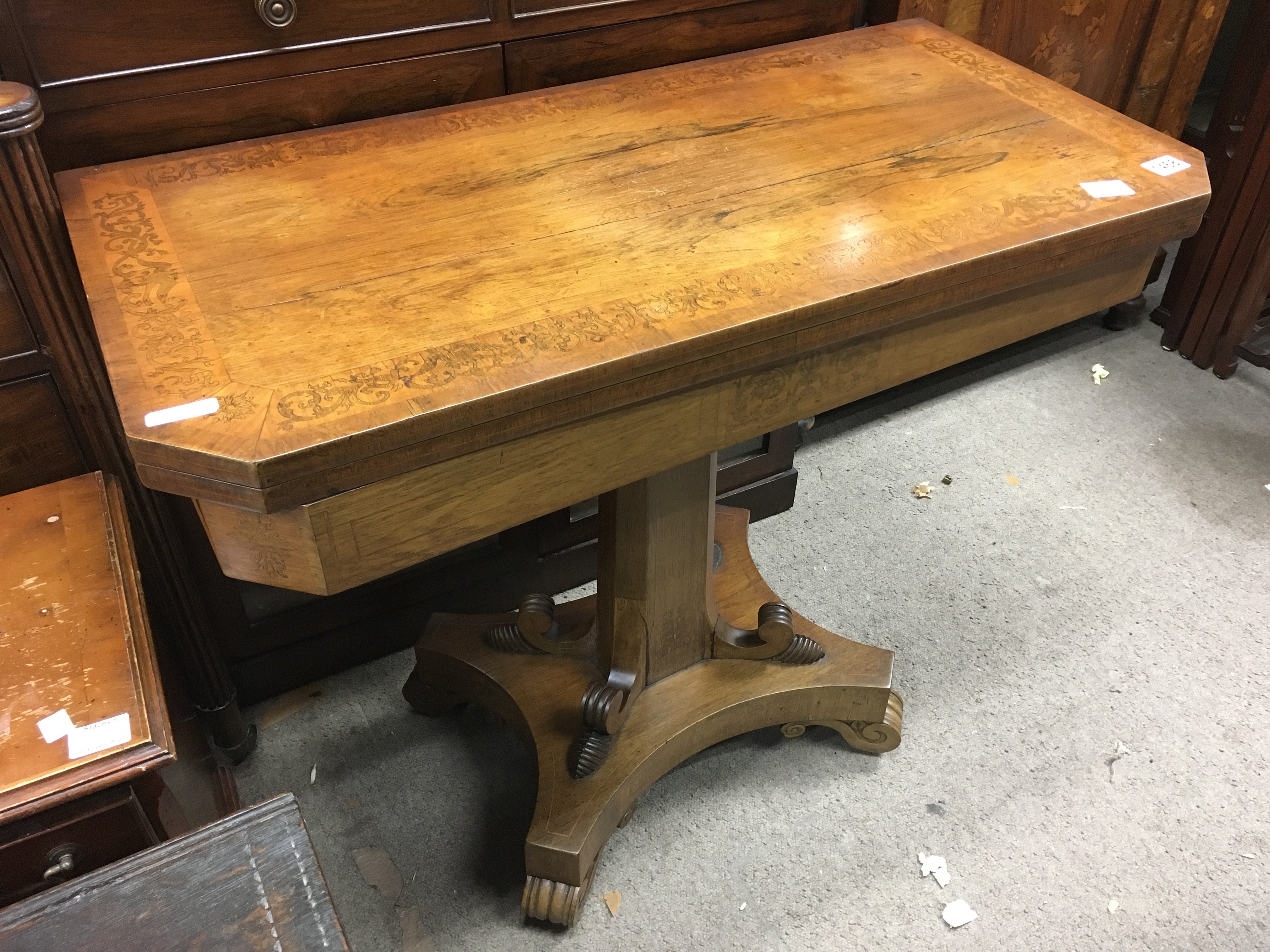 A Victorian walnut card table, the inlaid twin flat top above a shaped colour non a plinth base