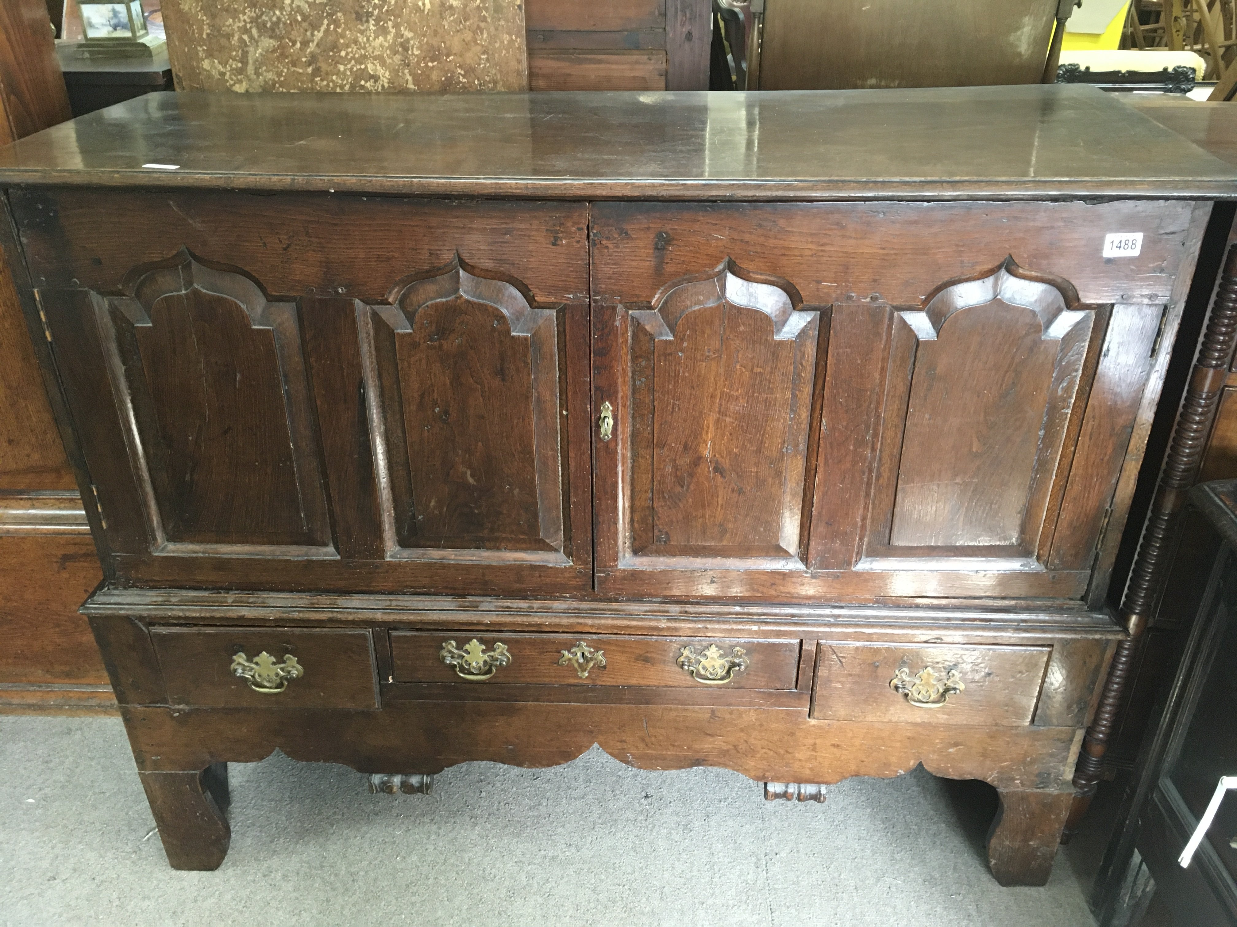 An 18th Century oak cupboard on stand, with a pair of panelled doors with three drawers under
