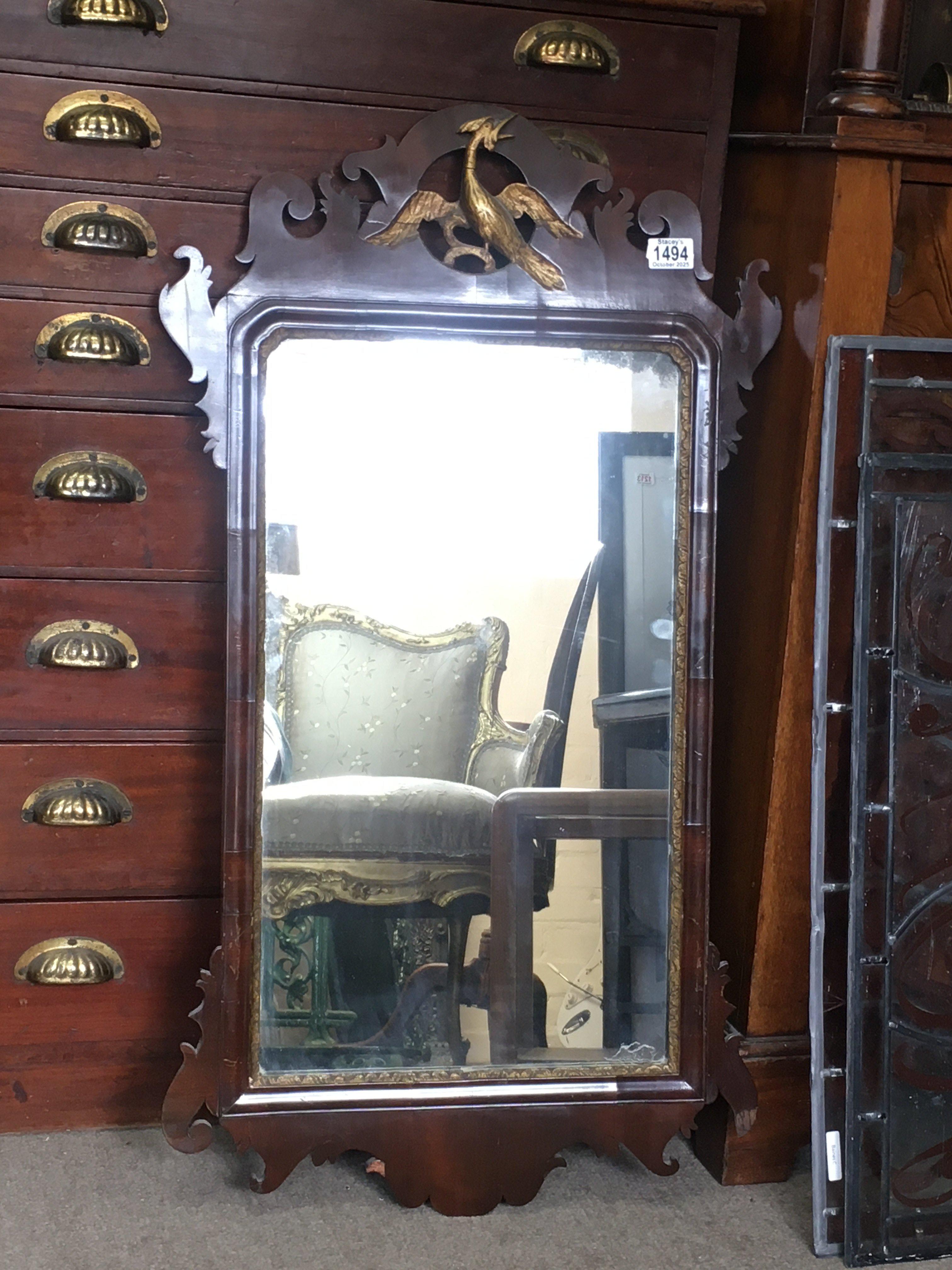 A Georgian mahogany wall mirror, the carved pediment in the form of a stylised bird. 45cm x 95cm