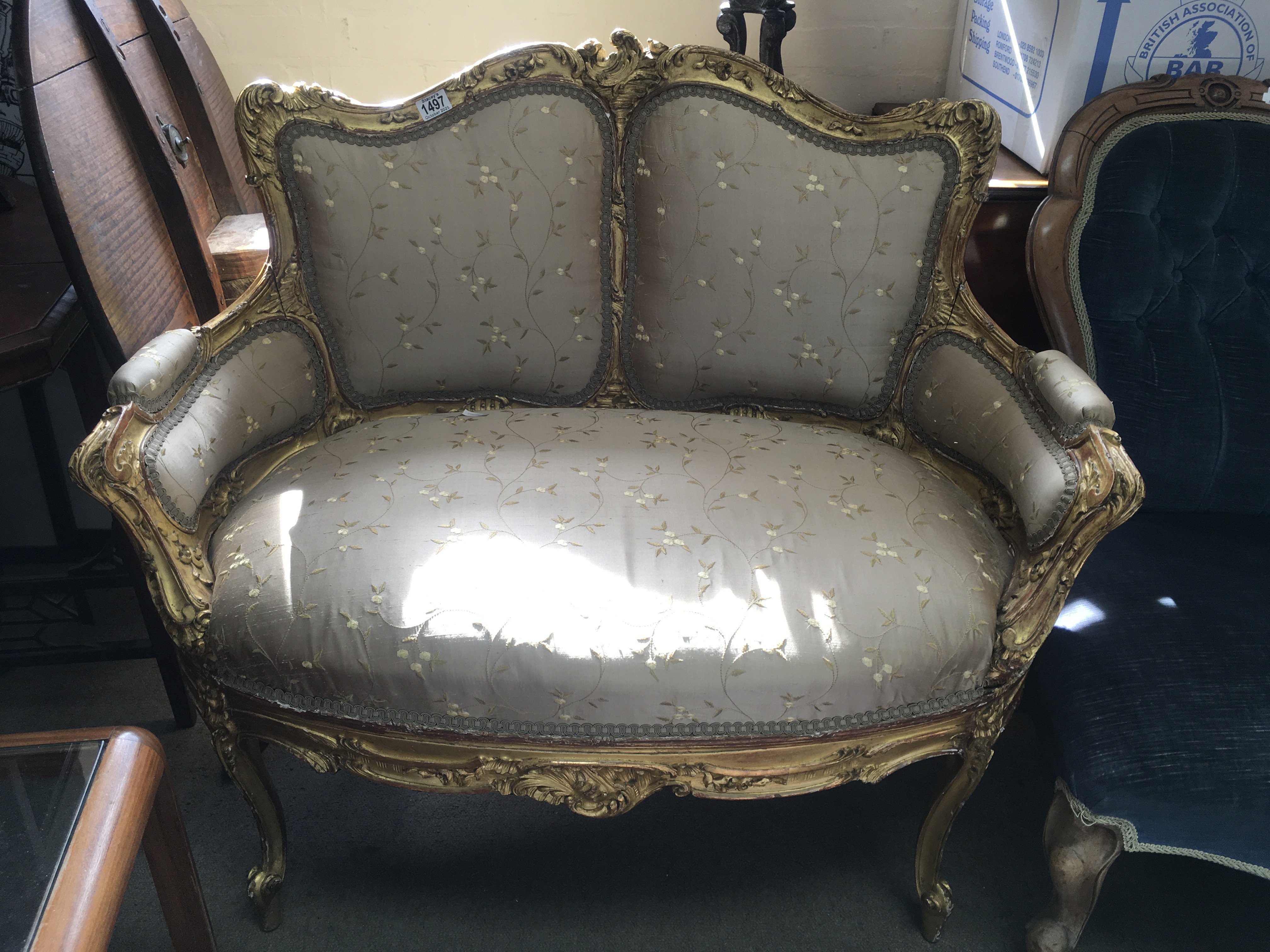A French Rococo-style love seat. The upholstered back and seat above cabriole legs