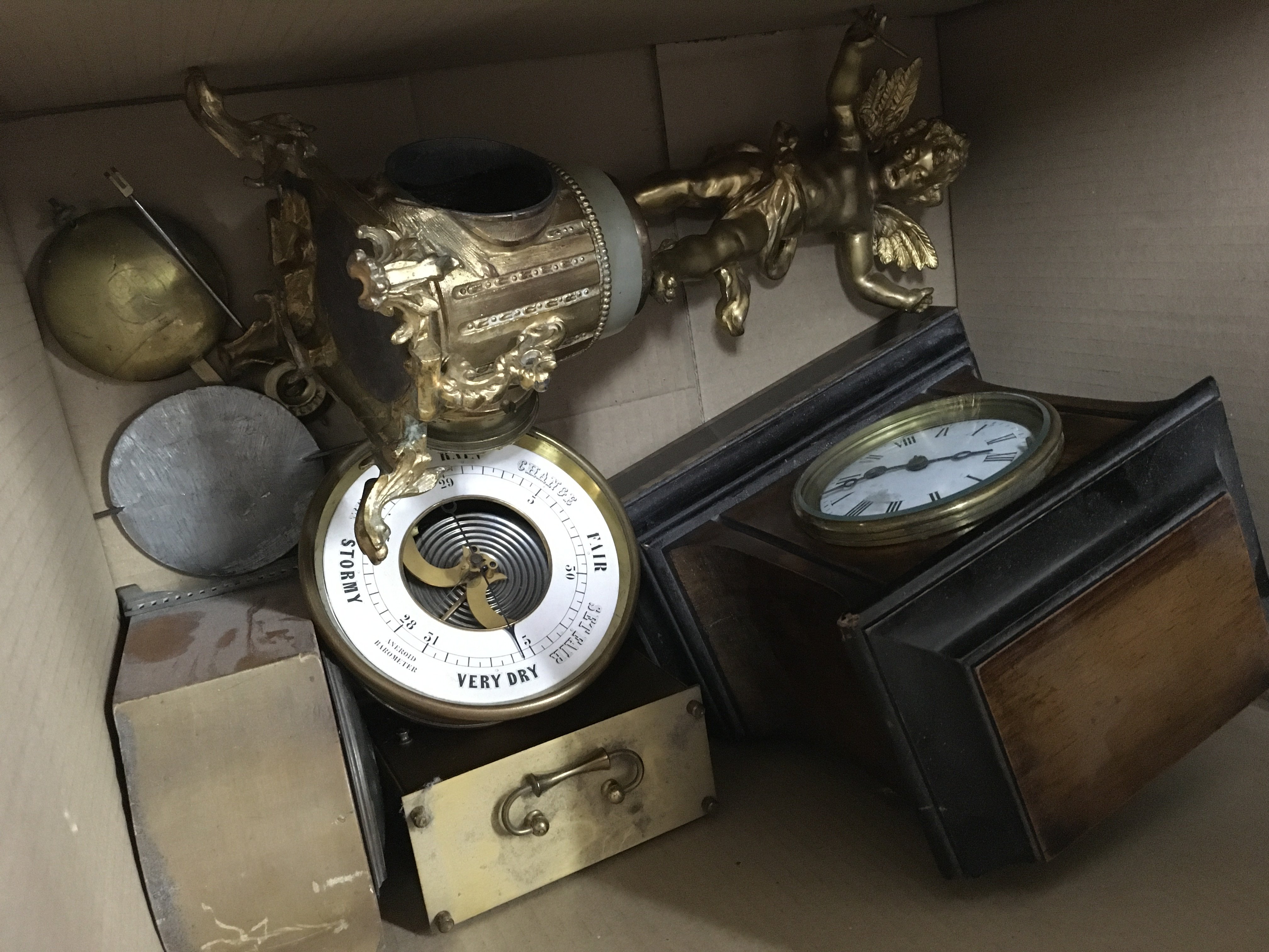 A box containing a collection of clocks and a barometer