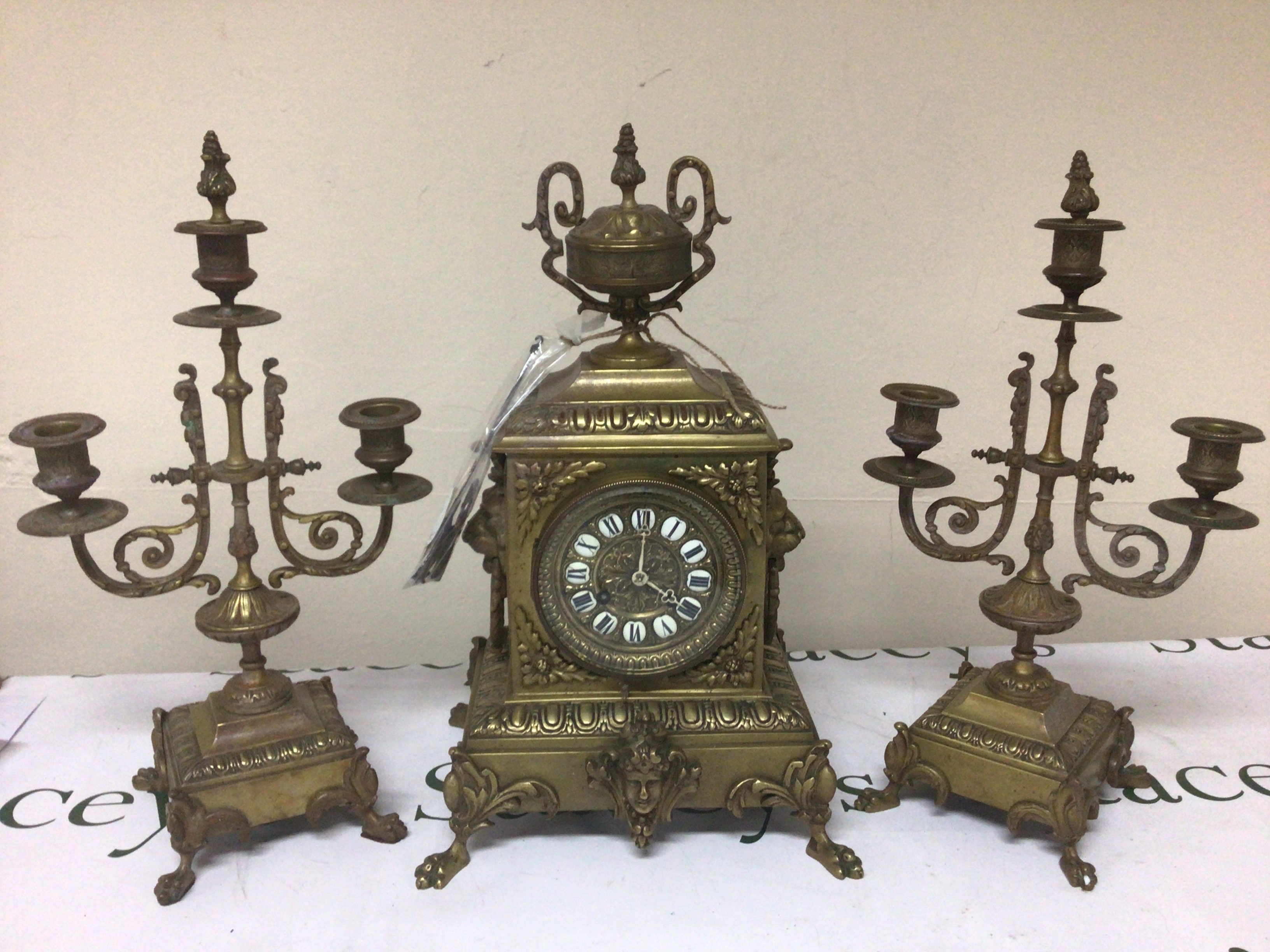 A brass cased late 19th century French clock the case surmounted with loin masks and ring ornamentation and surmounted with a classic urn. With side ornaments key and pendulum. Height 42cm