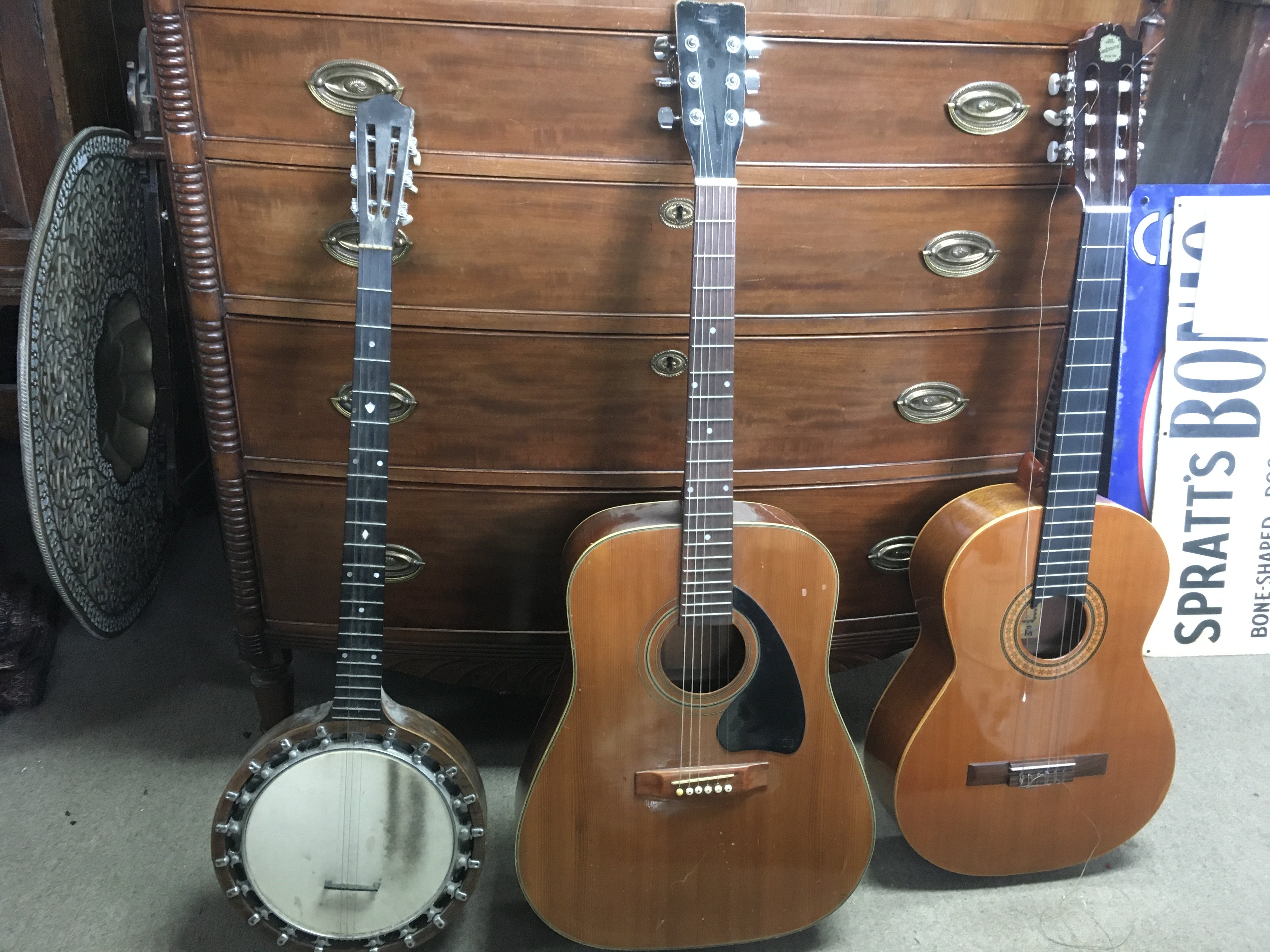 A Tapa Maciza Admira solid top classical style acoustic guitar, an unmarked acoustic guitar and a six string banjo. With one soft and one hard case