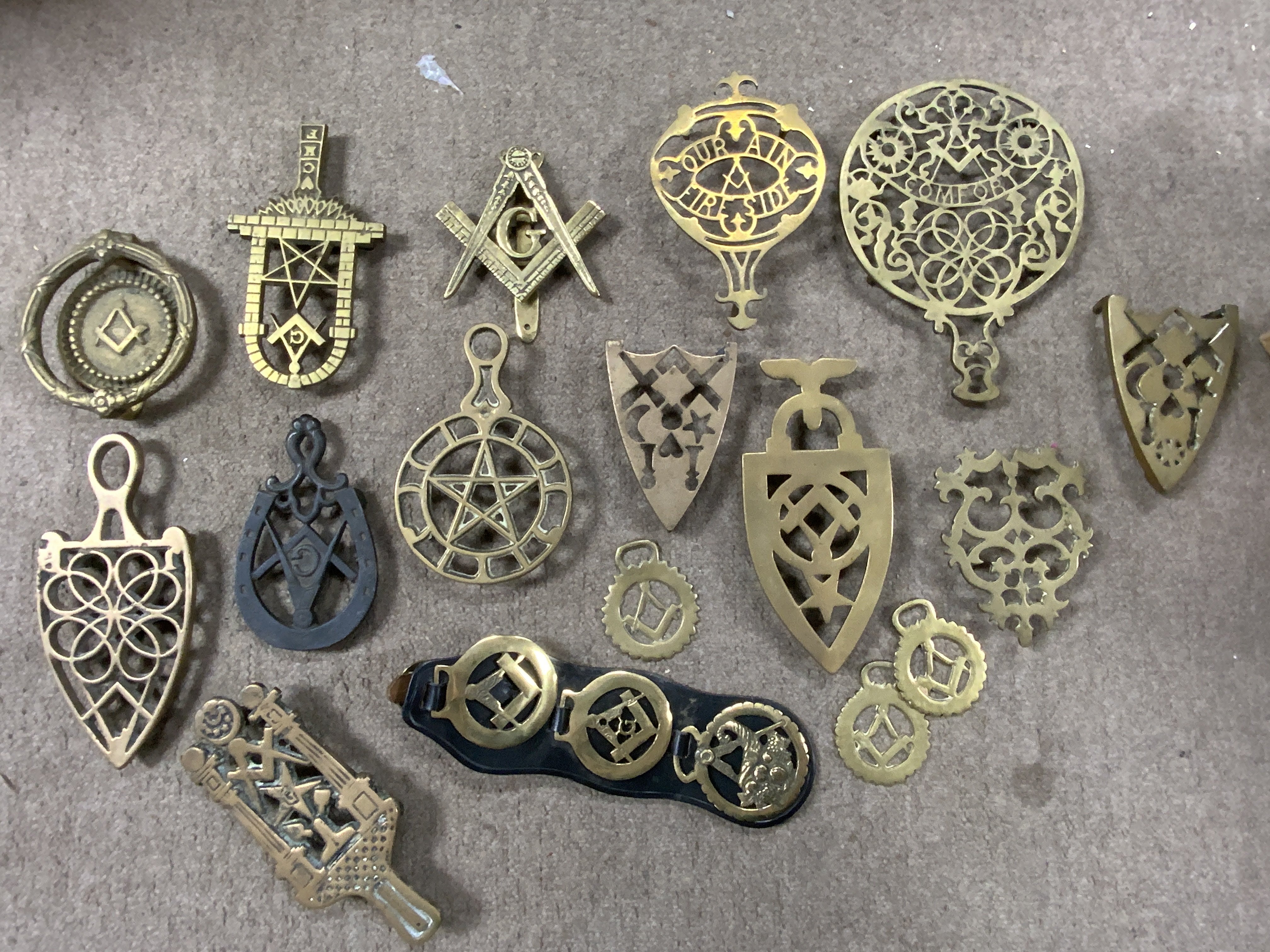 A collection of Masonic related brass trivets and horse brasses.