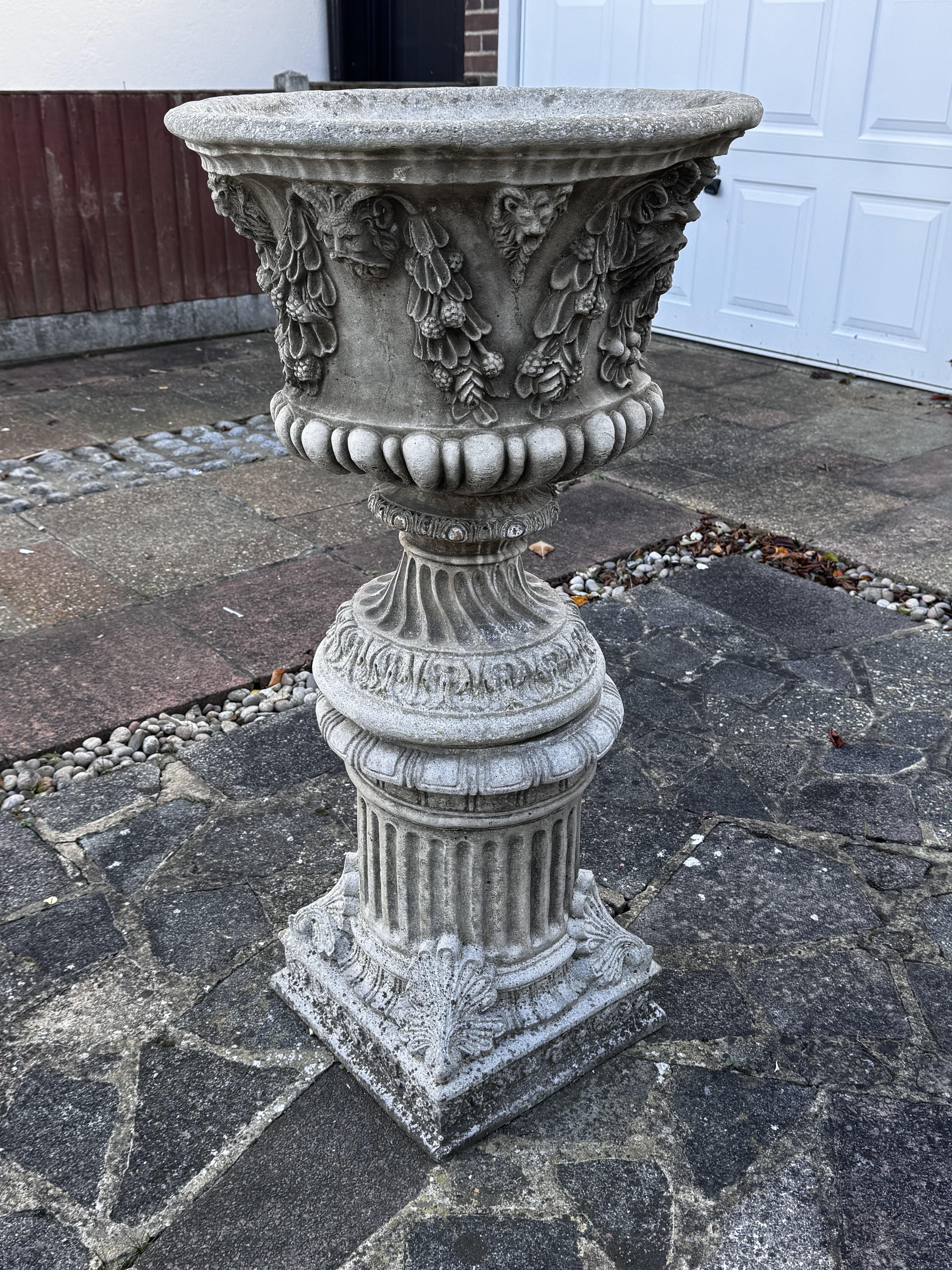A large cast concrete planter with grape vine design.