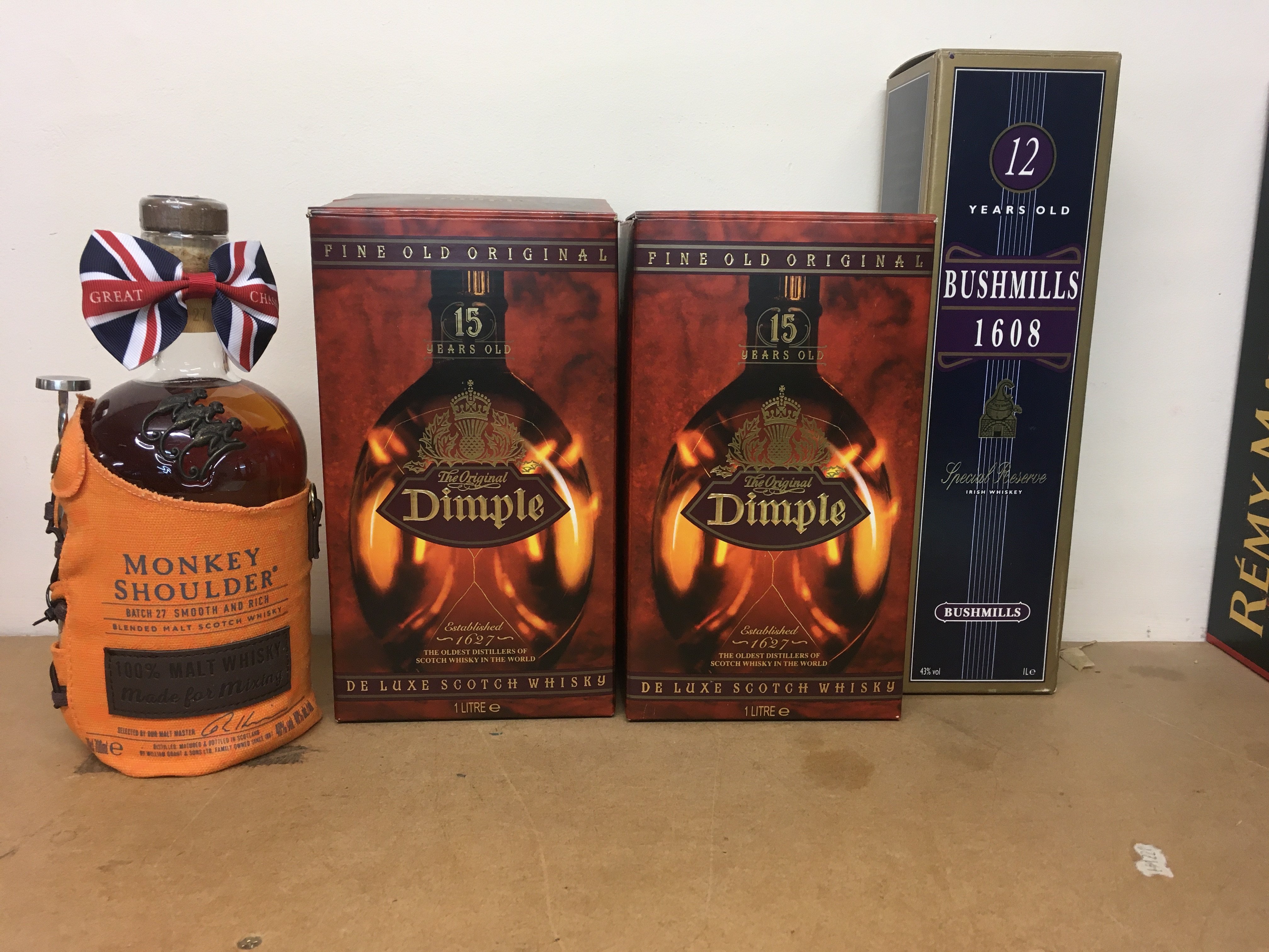 Four bottles of whiskey including Dimple , bushmills and monkey Shoulder .