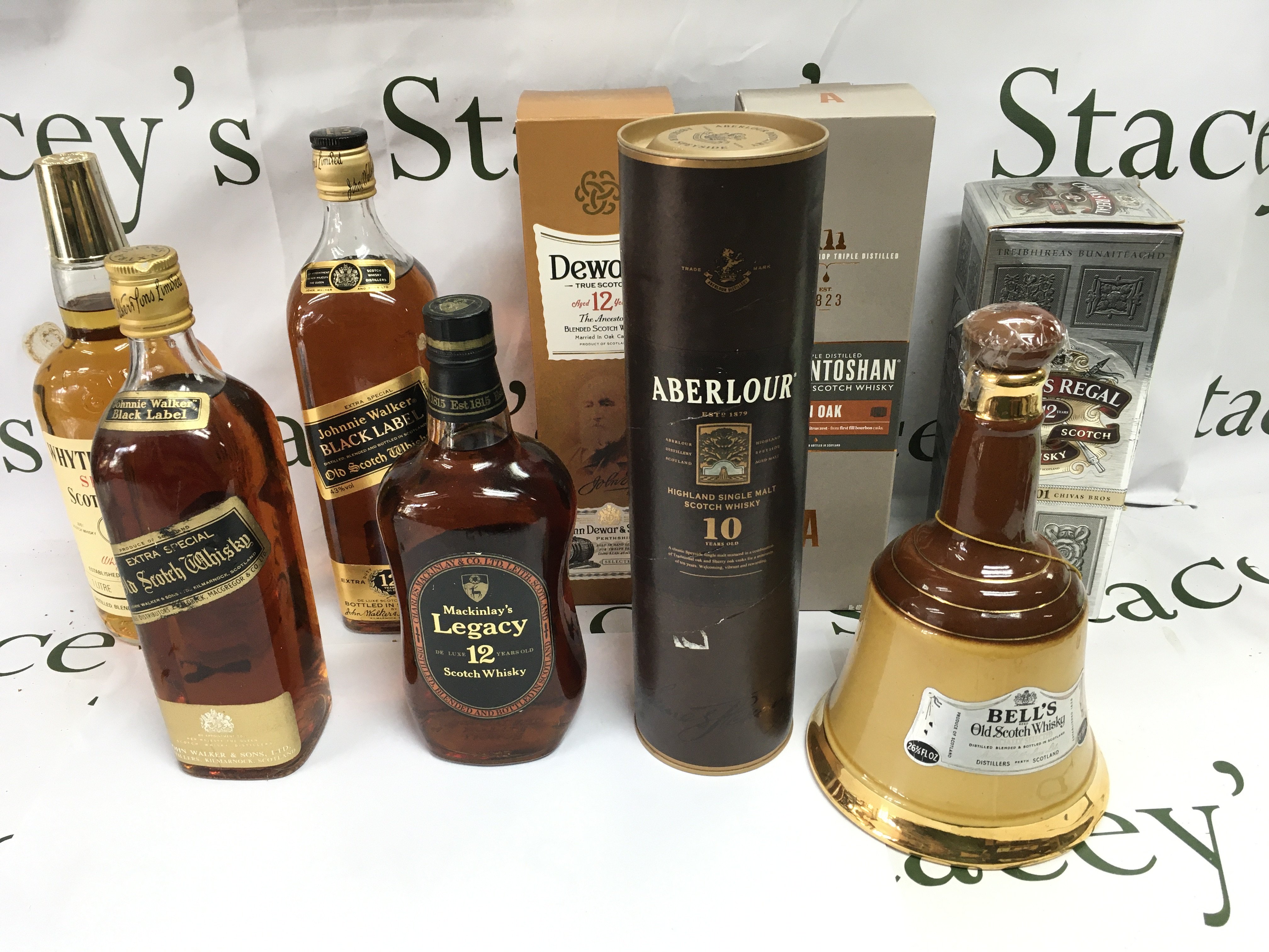A collection of 9 bottles of various whiskey including Dewars Johnnie Walker bells etc