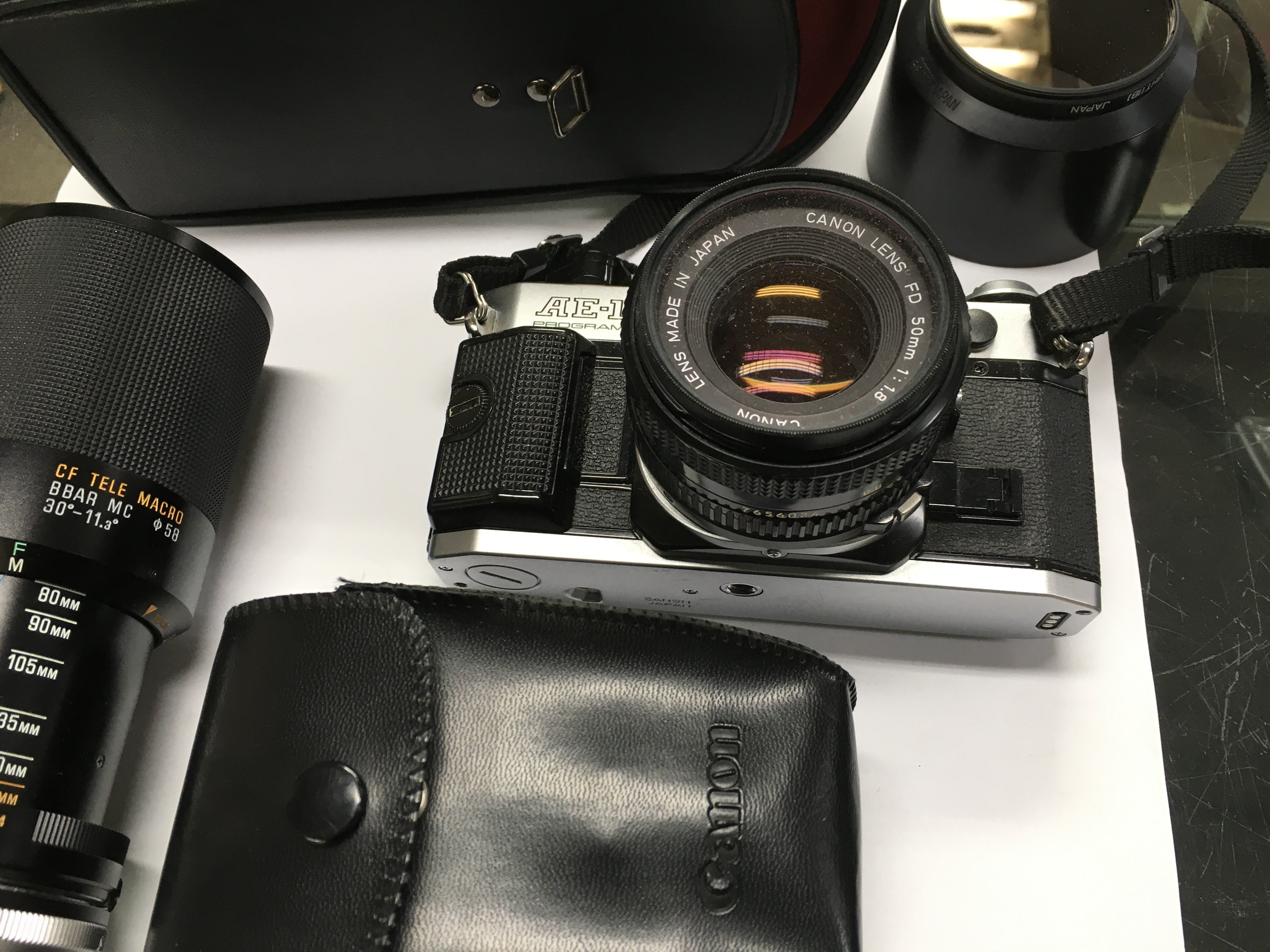 A canon AE-1 camera with additional lenses and a flash with other accessories.
