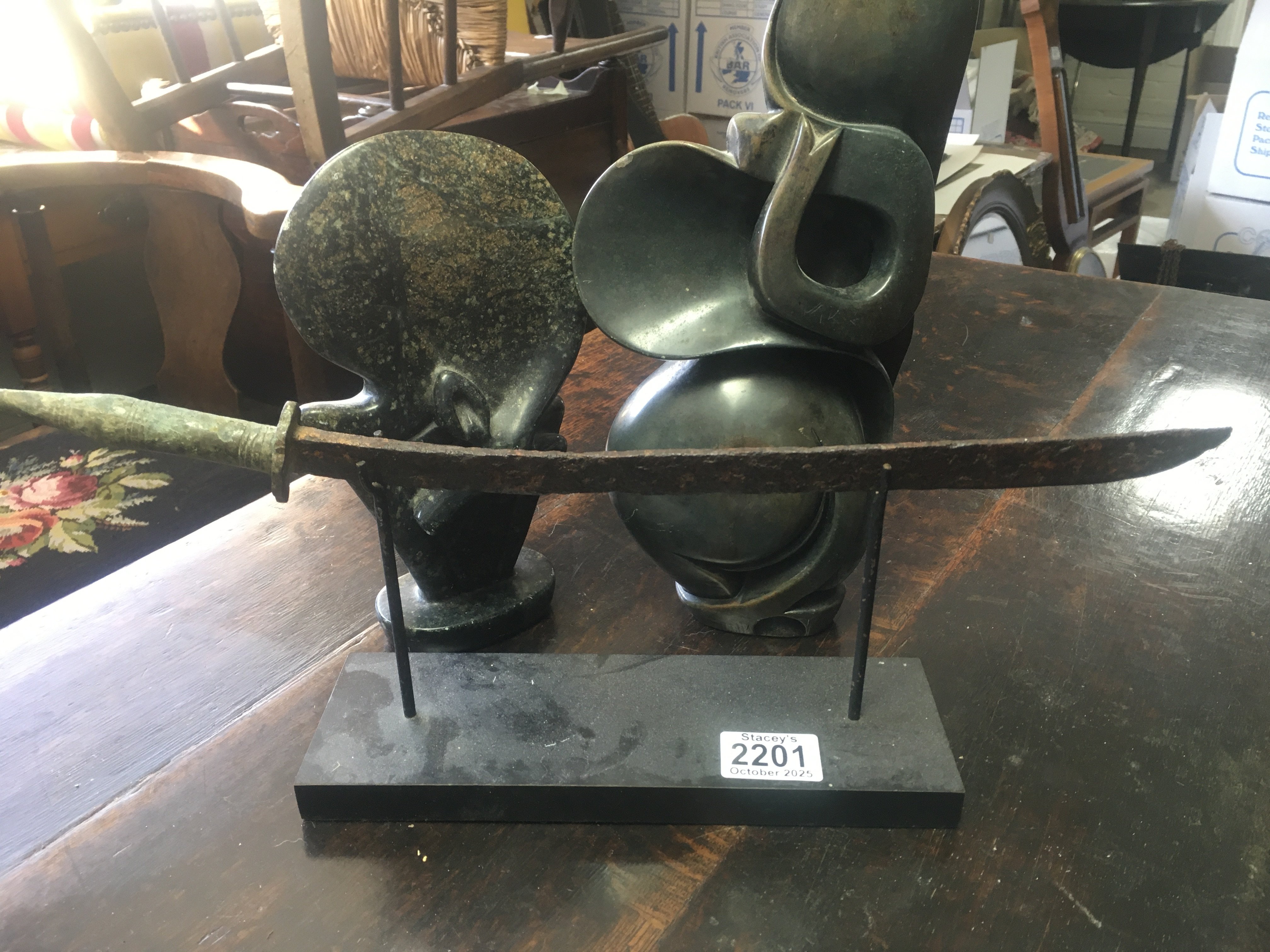 Two Shona style stone carvings Ann&#2013266057۪s a sword on stand .